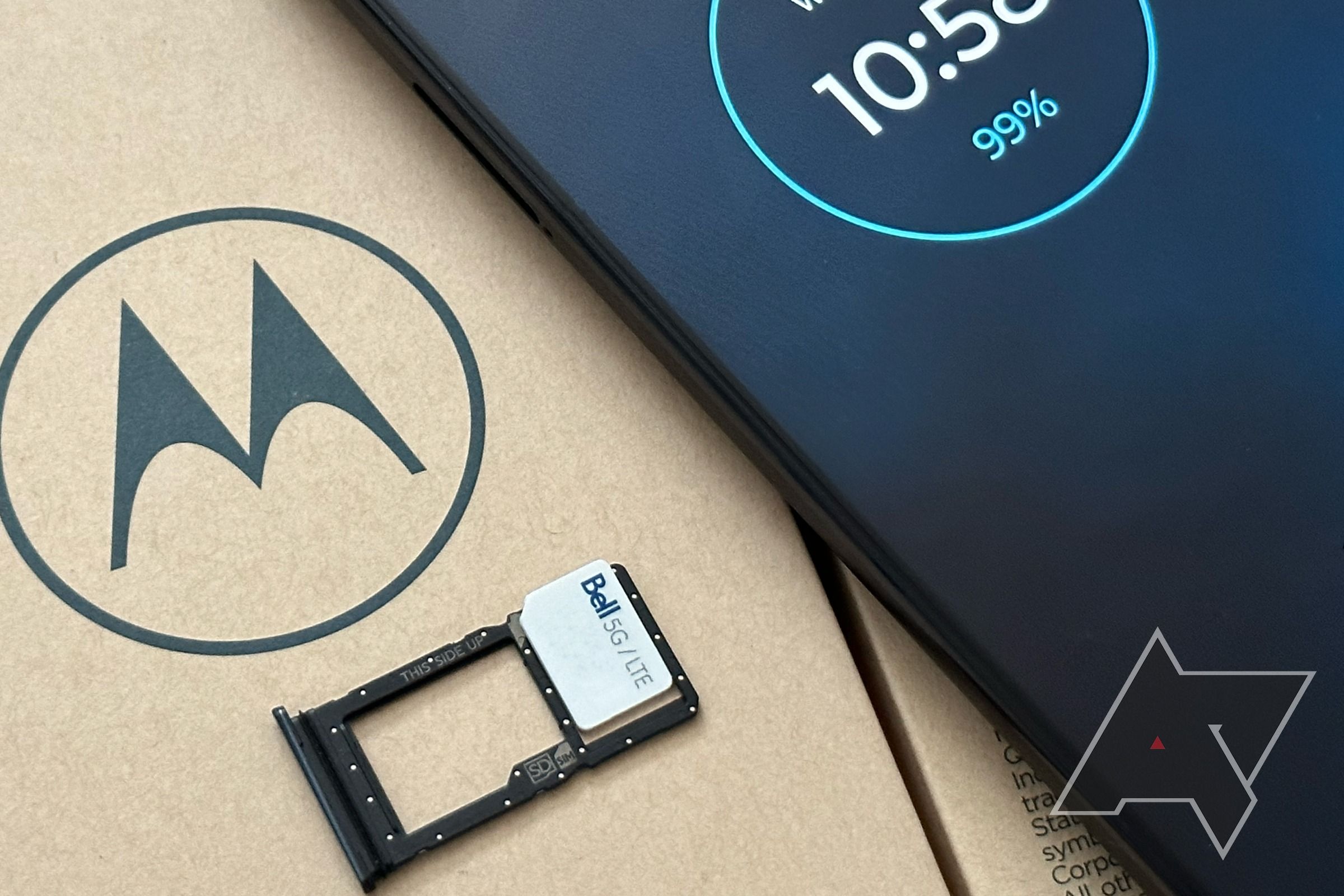 Um cartão SIM em cima de uma bandeja de cartão SIM retirado de um Motorola G Stylus 5G em cima de uma caixa marrom com o logotipo da Motolora