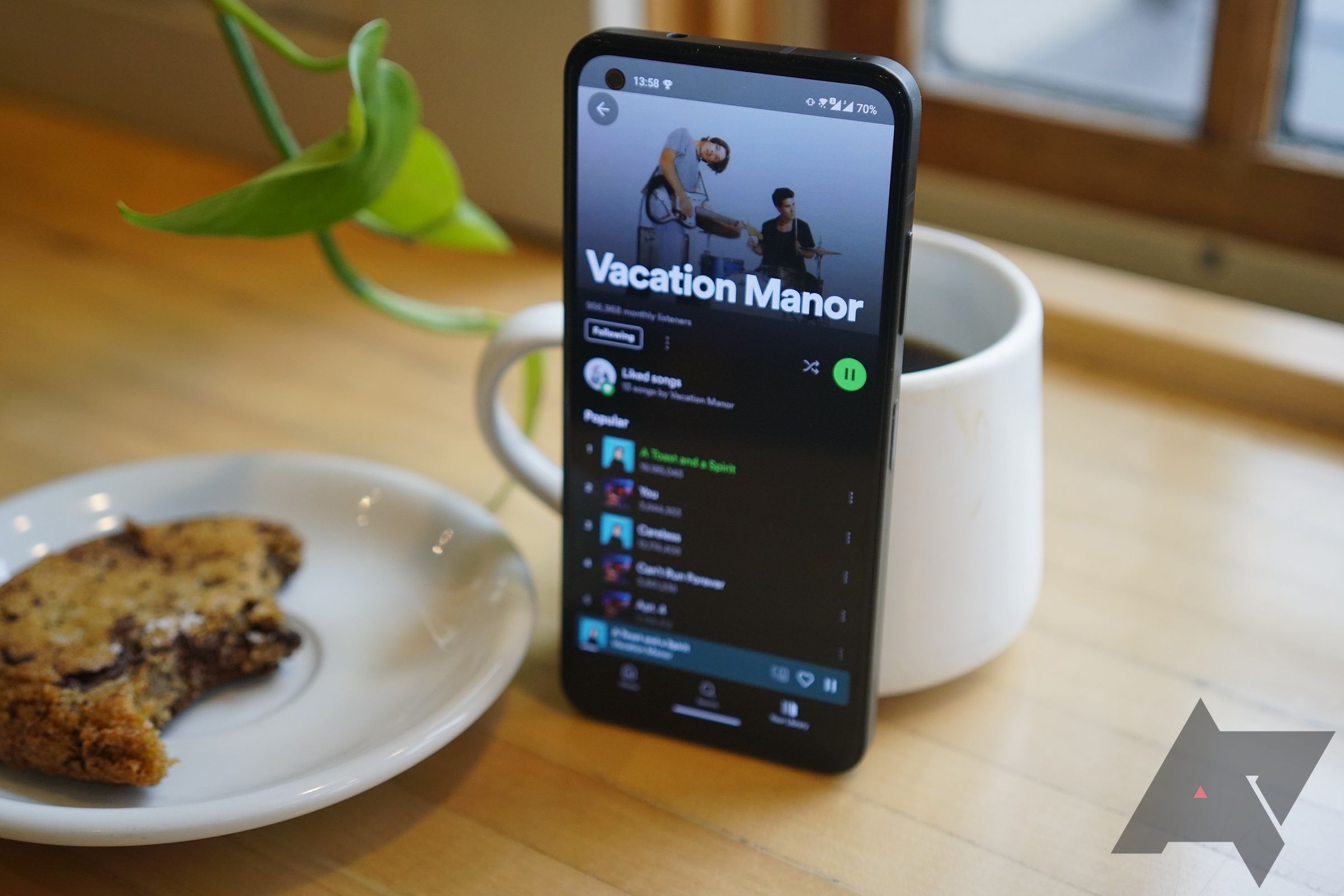 Um smartphone com o aplicativo Spotify aberto em uma mesa com uma caneca atrás dele