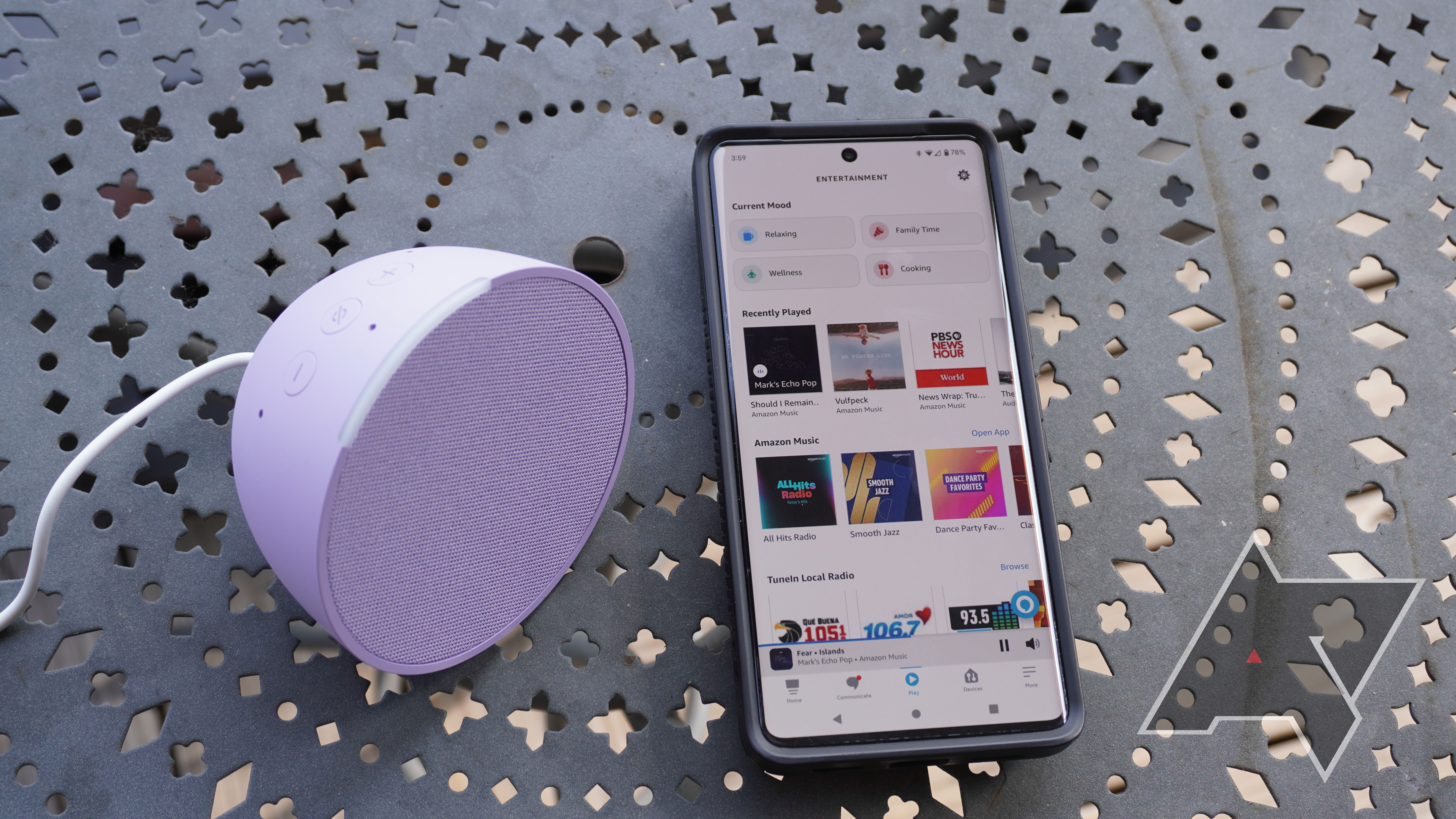 Um Amazon Echo Pop roxo e um smartphone em uma mesa de metal