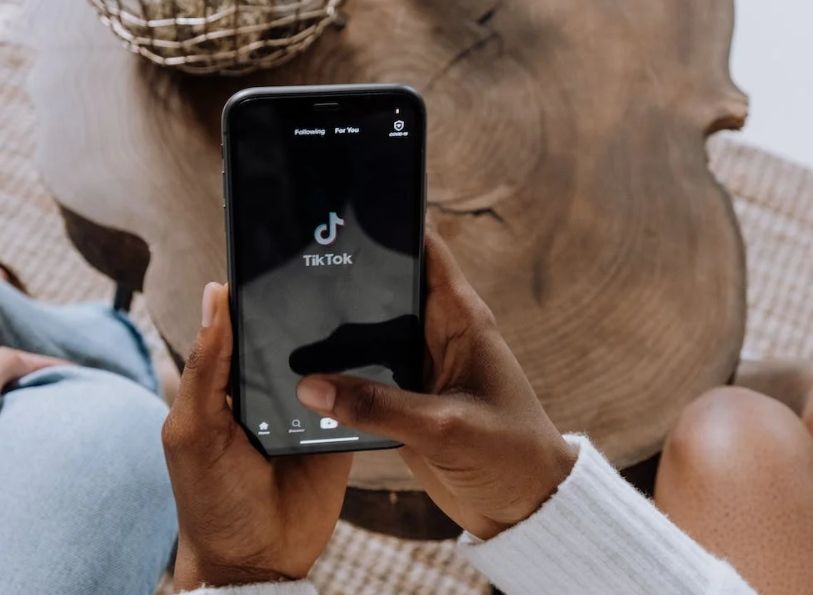 Pessoa abrindo o aplicativo TikTok no smartphone.