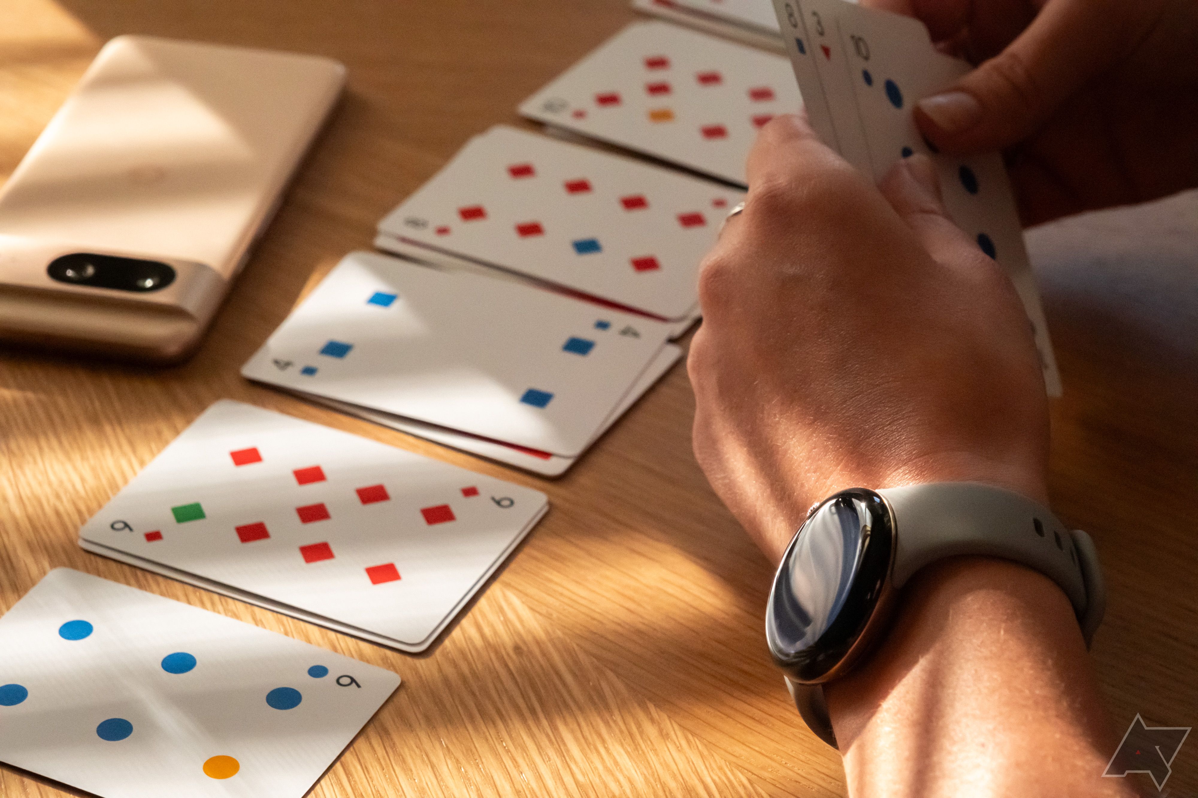 Uma pessoa usa um Google Pixel Watch 2 enquanto joga cartas.