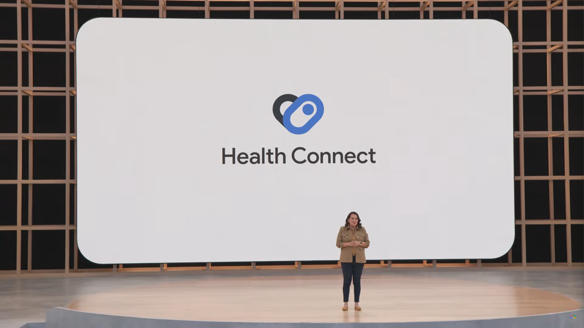 Uma pessoa está no palco durante o Google I/O em frente a uma tela grande com as palavras 