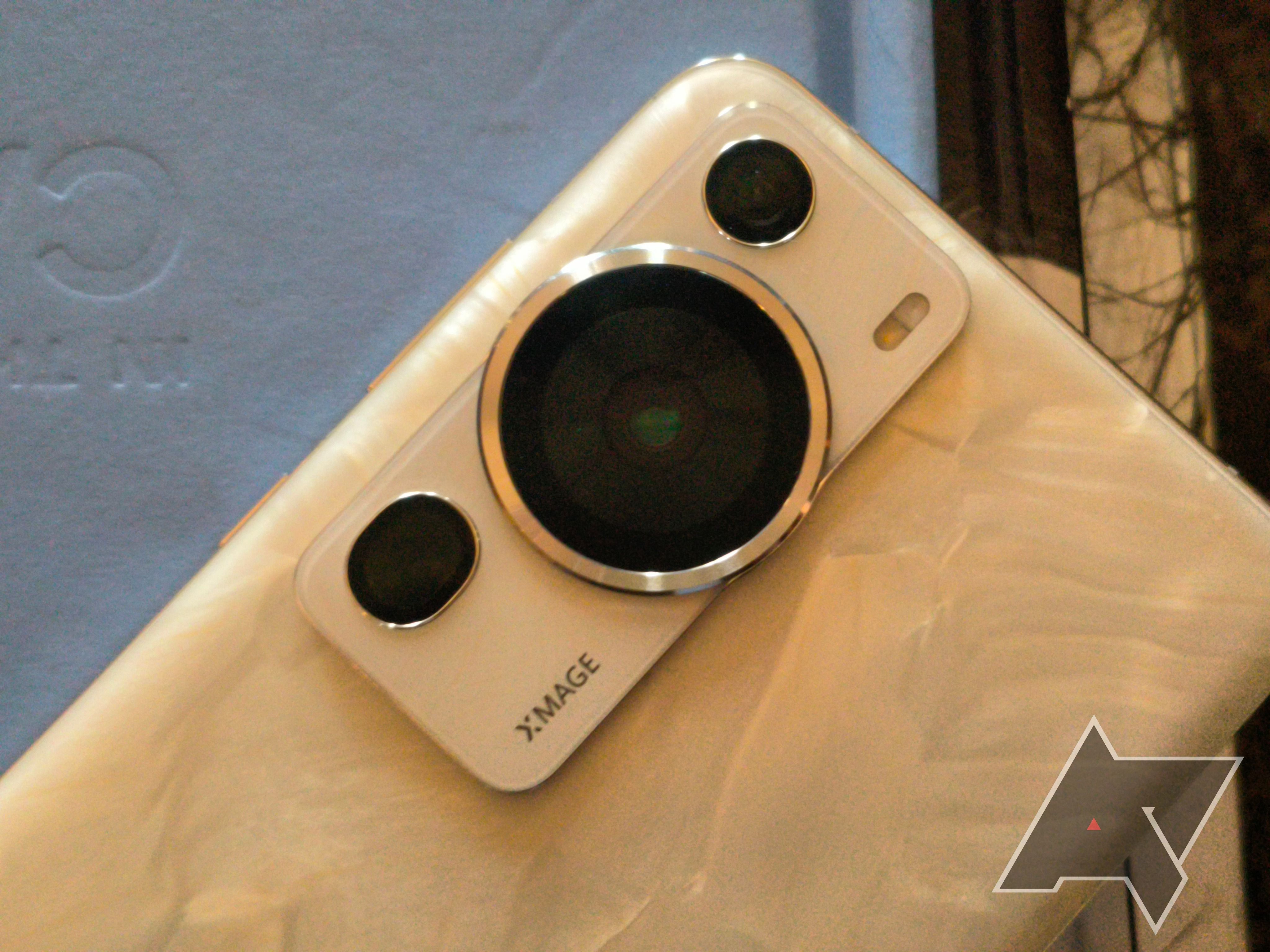 Um módulo de câmera dourado de um telefone Huawei em cima de um notebook cinza sobre uma mesa de mármore.