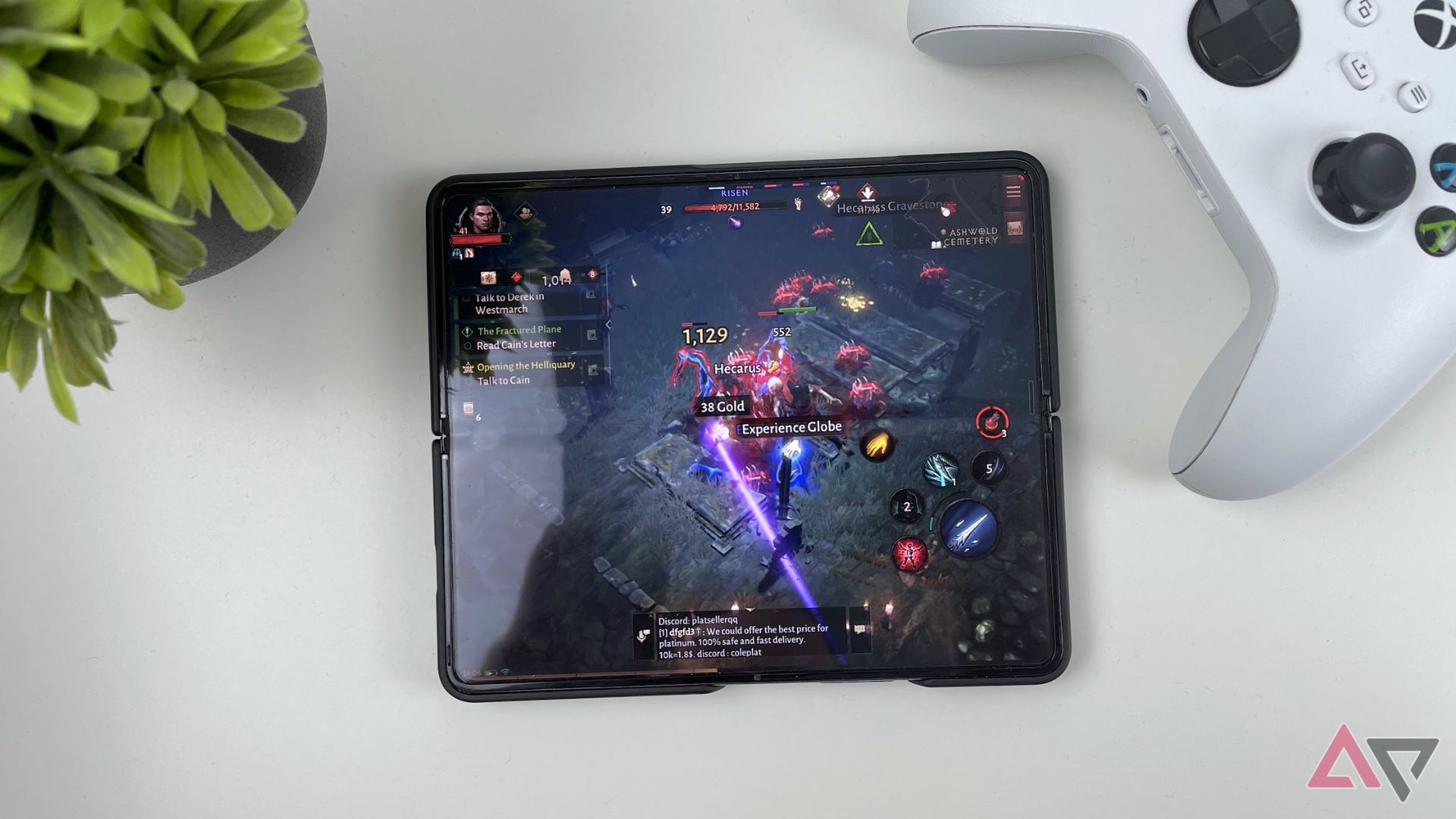 Jogando Diablo no Galaxy Z Fold 4 em uma mesa ao lado de uma planta e um controle de Xbox