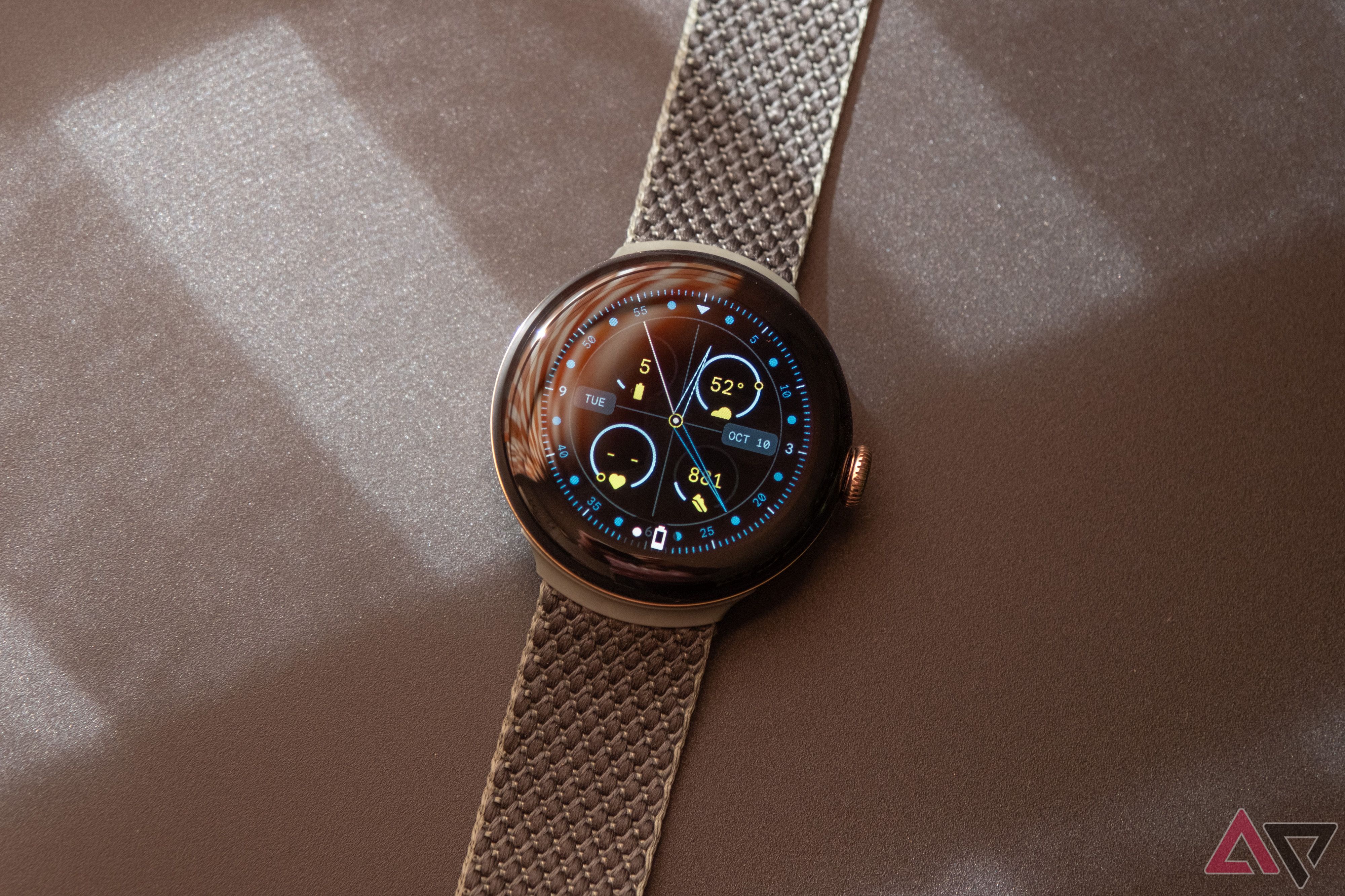 Um Google Pixel Watch repousa sobre uma superfície com textura marrom