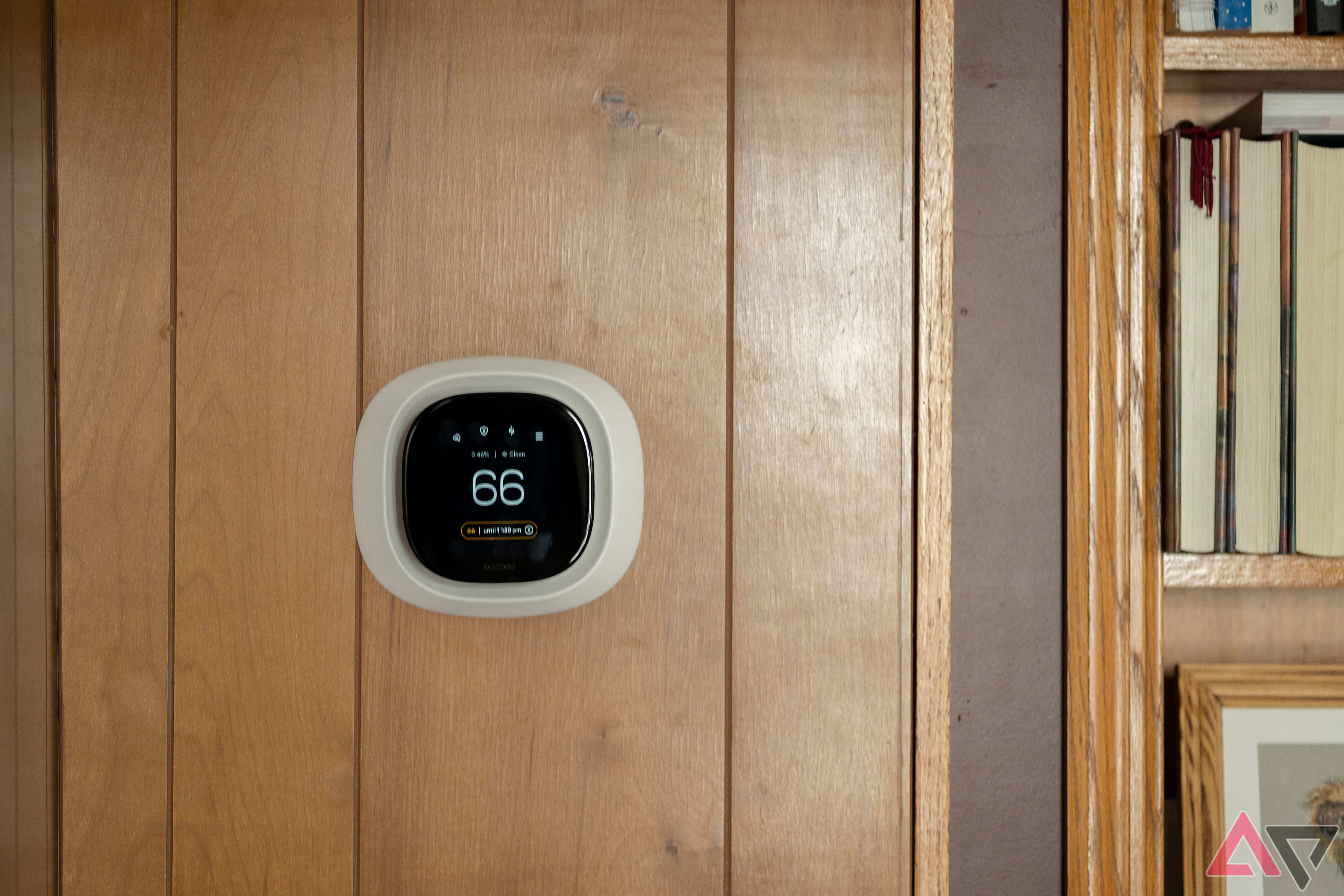 Ecobee Premium Smart Thermostat na parede com painéis de madeira ao lado da estante
