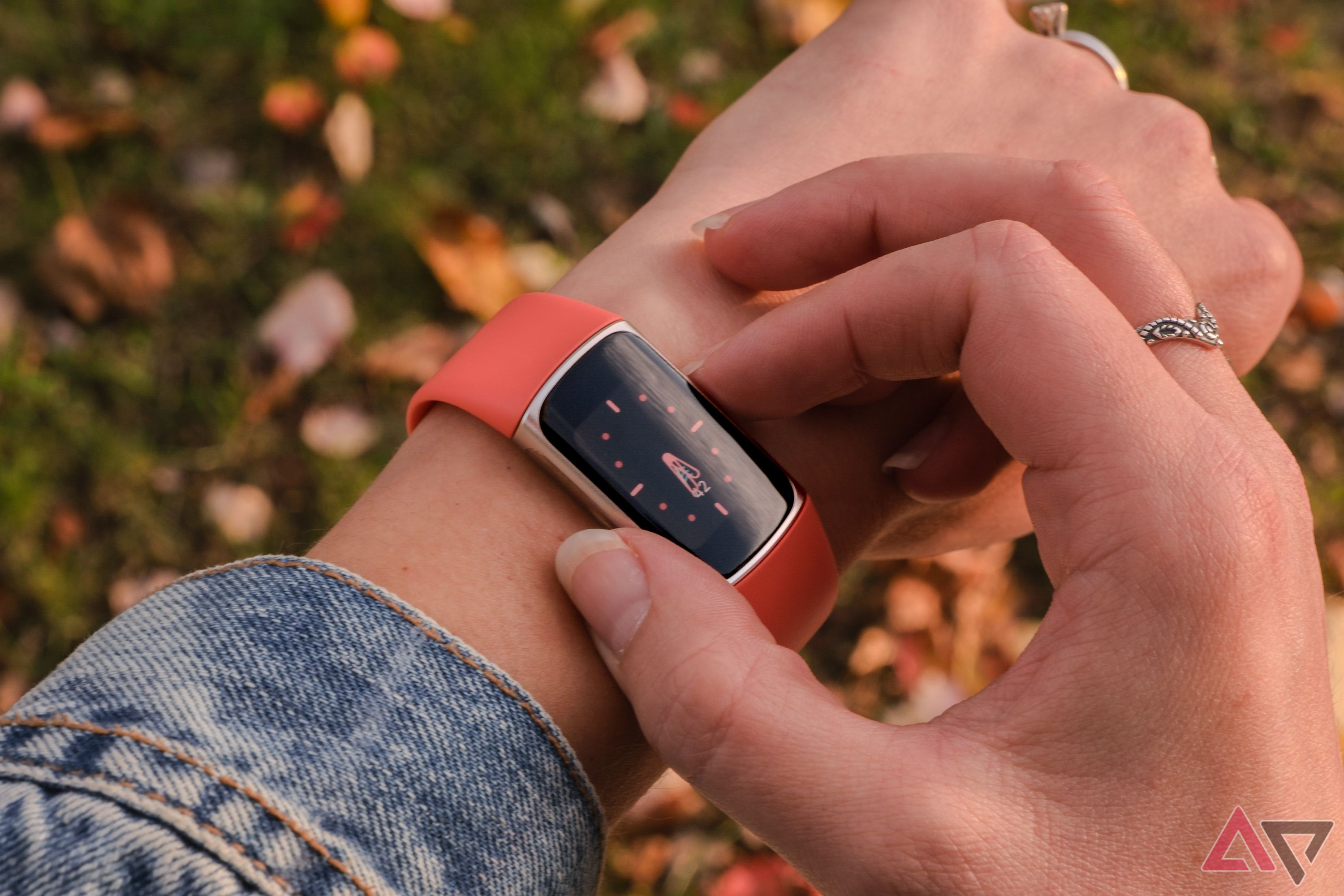 Um Fitbit Charge 6 com uma pulseira laranja e usado no pulso