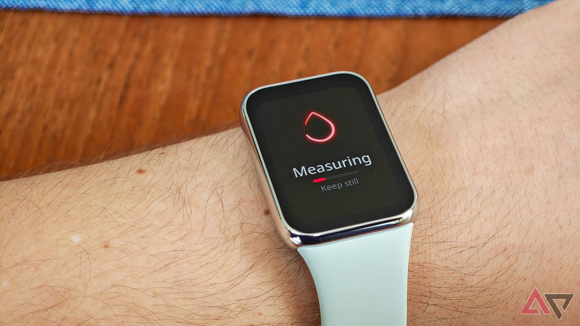 Xiaomi Smart Band 8 Pro com uma pulseira cinza no pulso de um homem caucasiano mostrando uma medição de frequência cardíaca em andamento