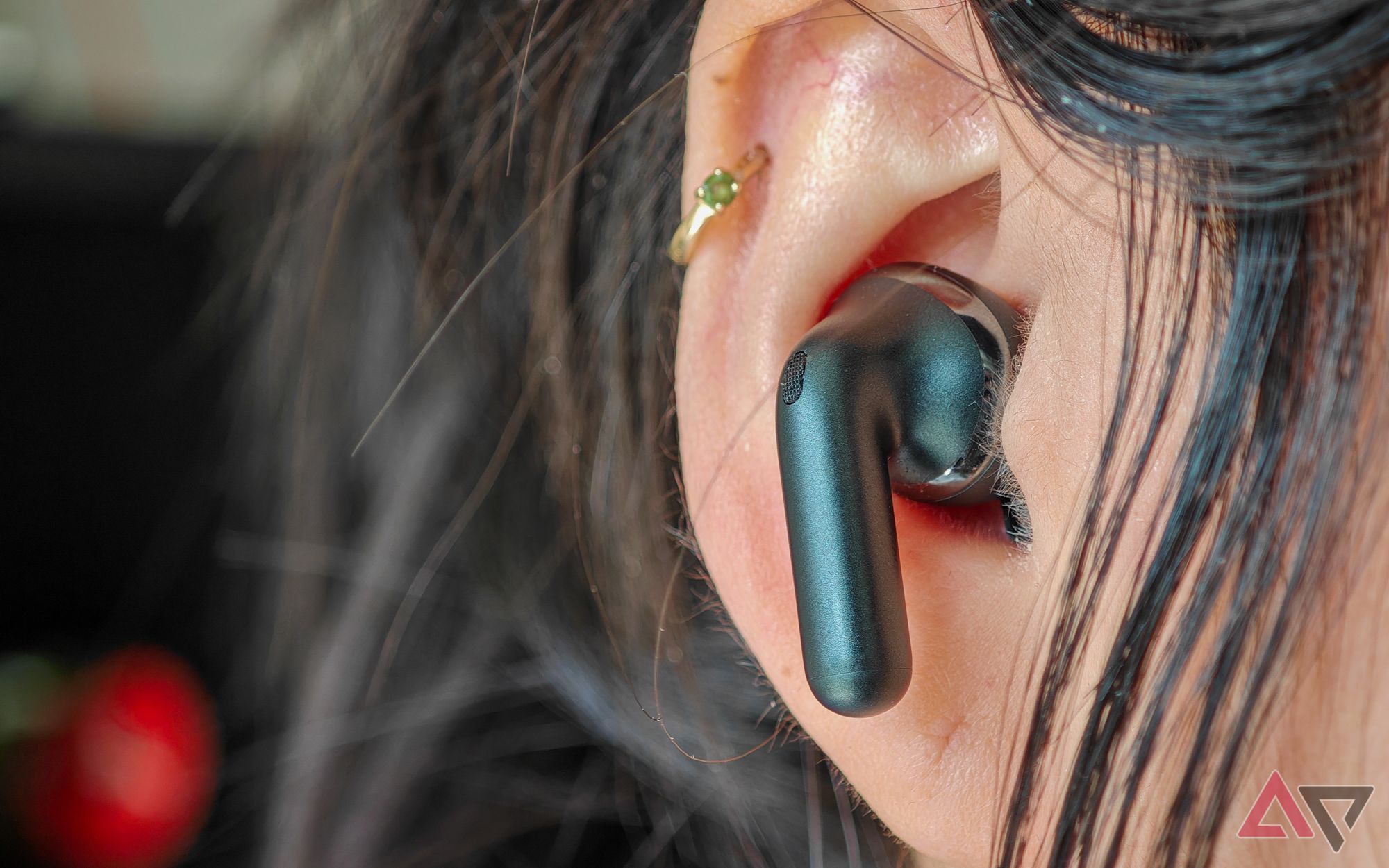 O Moto Buds+ em preto com um único fone de ouvido mostrado na orelha de uma mulher
