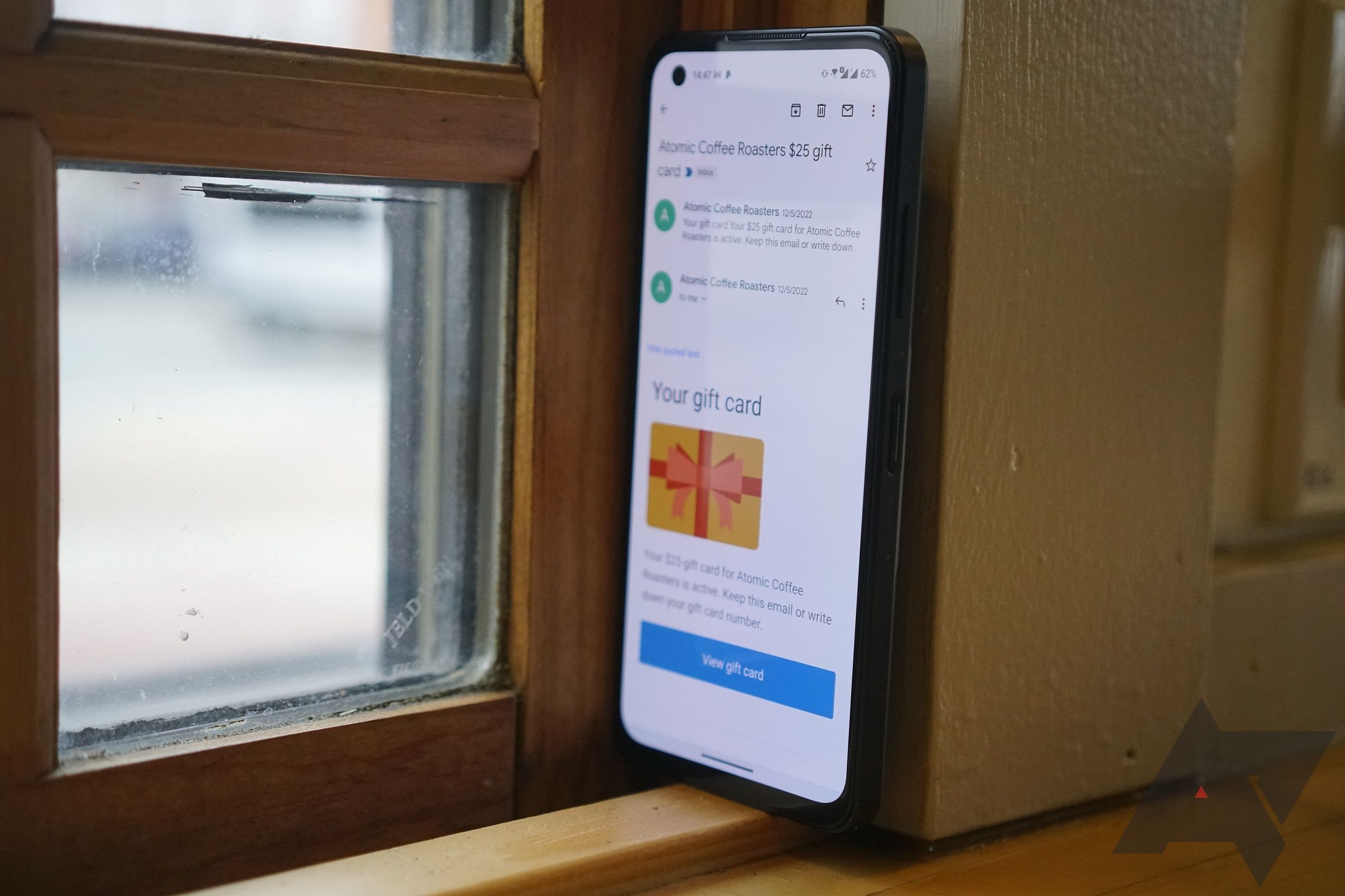 Telefone Android ao lado da janela com display mostrando o aplicativo Gmail.