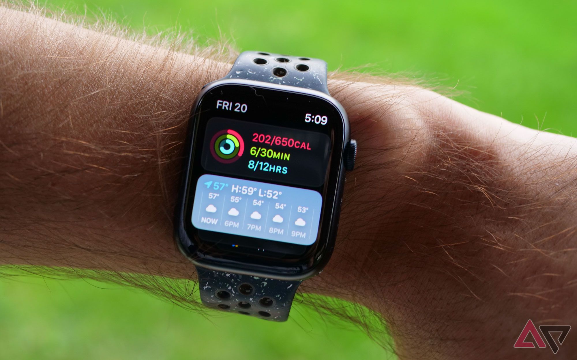 Um Apple Watch no pulso exibindo informações sobre condicionamento físico e clima