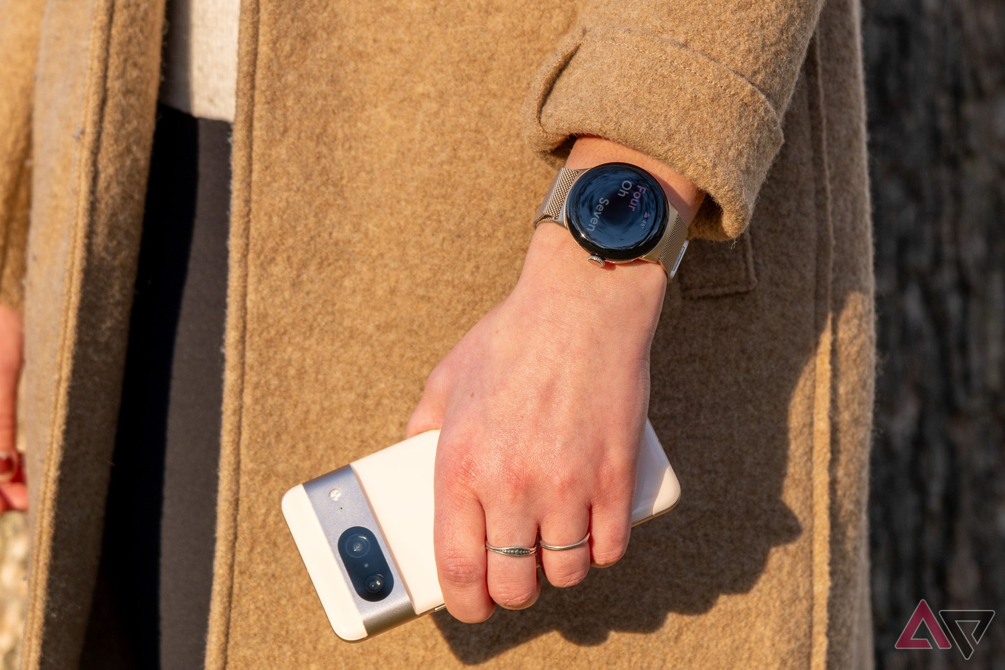 Uma pessoa usando um Google Pixel Watch no pulso e segurando um telefone Google Pixel 8.