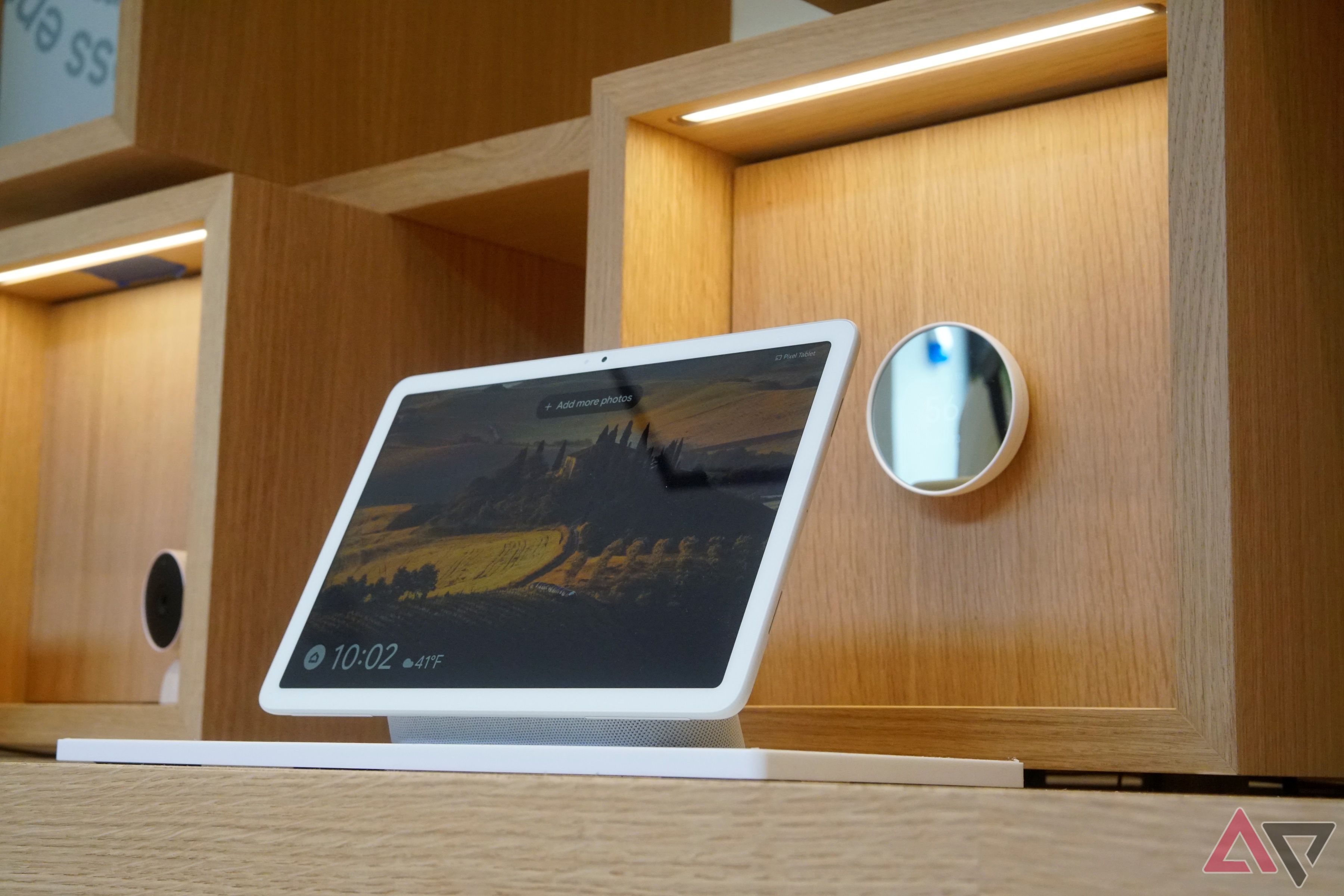 Um Pixel Tablet sobre uma mesa com um termostato Nest em uma parede ao fundo.