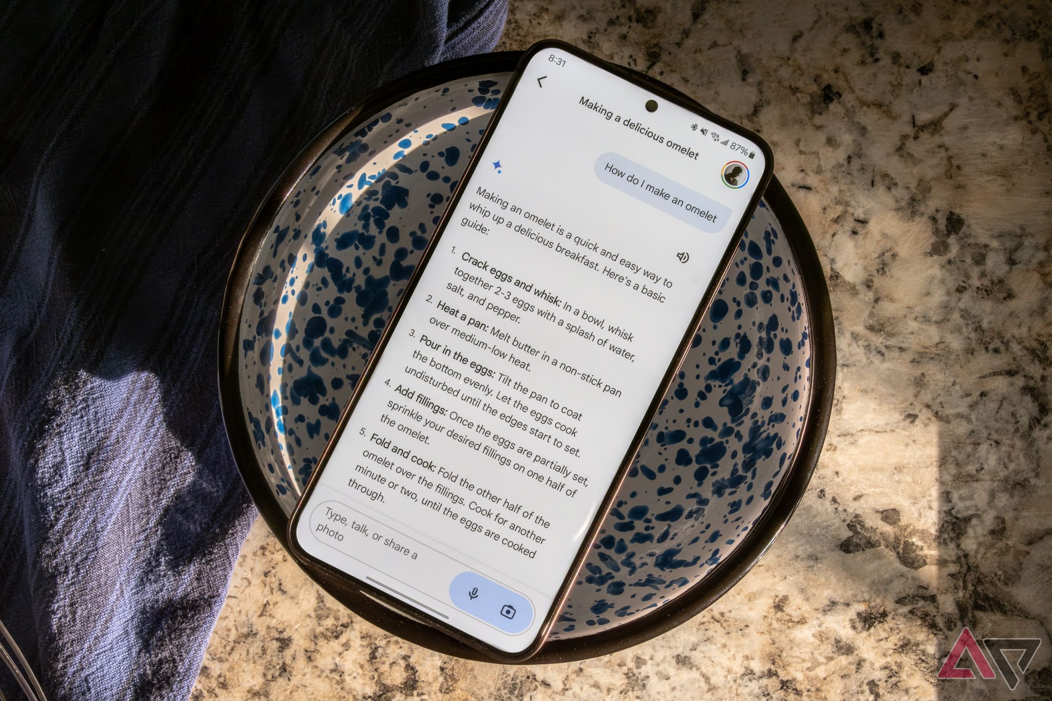 Um smartphone Samsung em uma tigela, mostrando uma receita de omelete no Google Gemini
