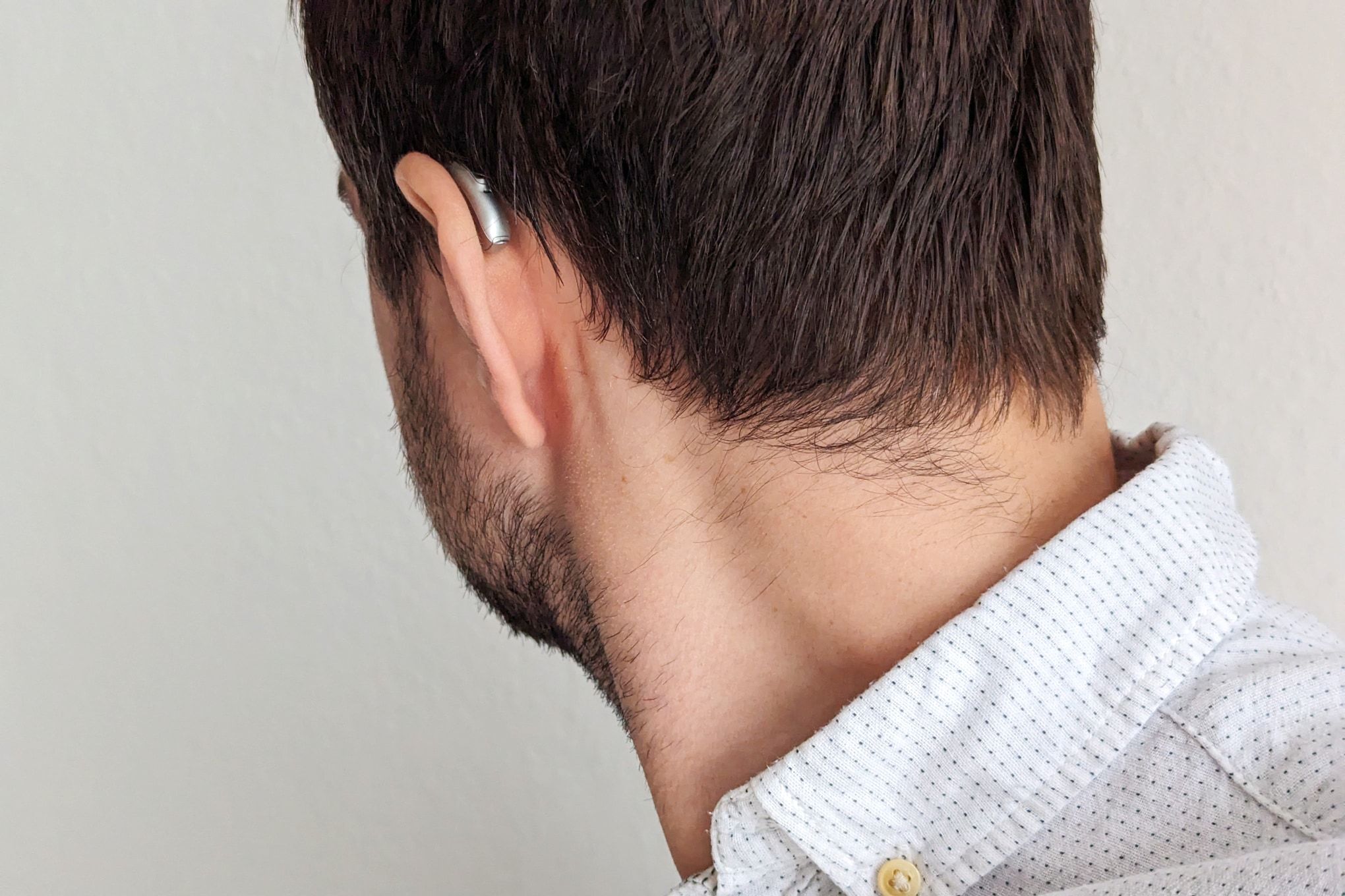 Um homem está de costas para a câmera, com um aparelho auditivo Phonak visível atrás da orelha