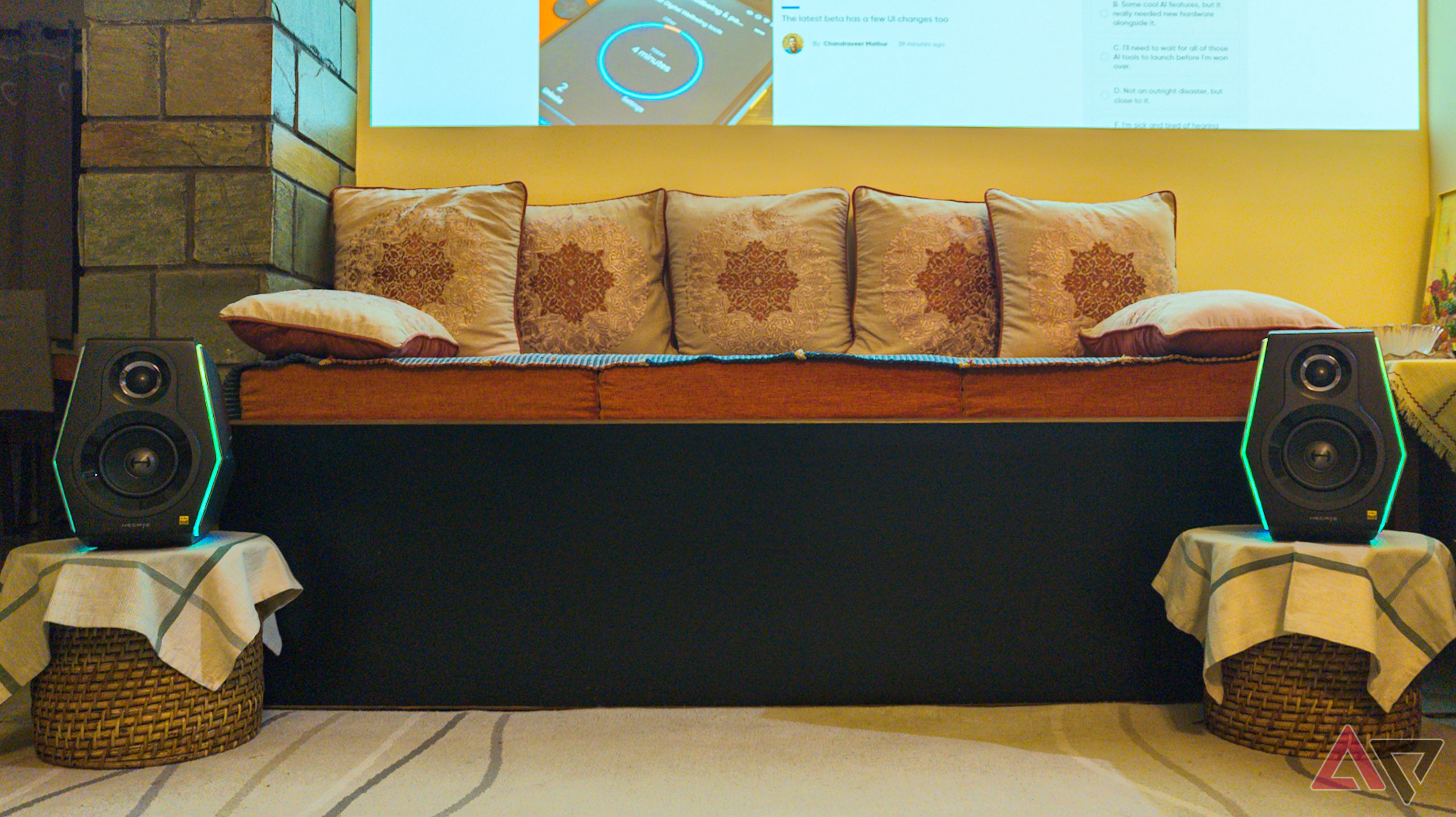Alto-falantes flanqueando um assento em uma sala de estar com uma tela de projetor visível ao fundo