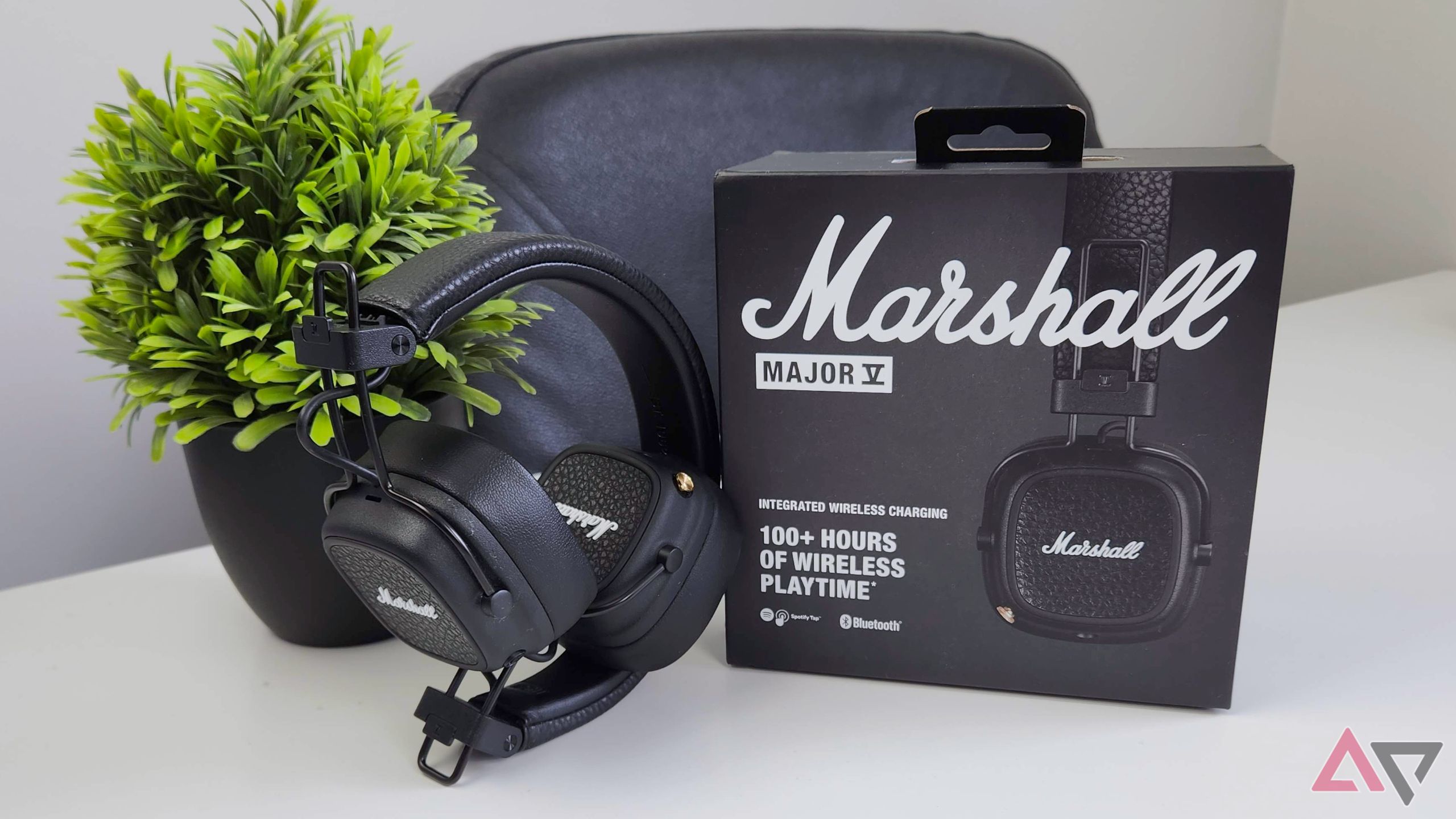 Fones de ouvido sem fio Marshall Major V em uma mesa ao lado de uma caixa e uma planta