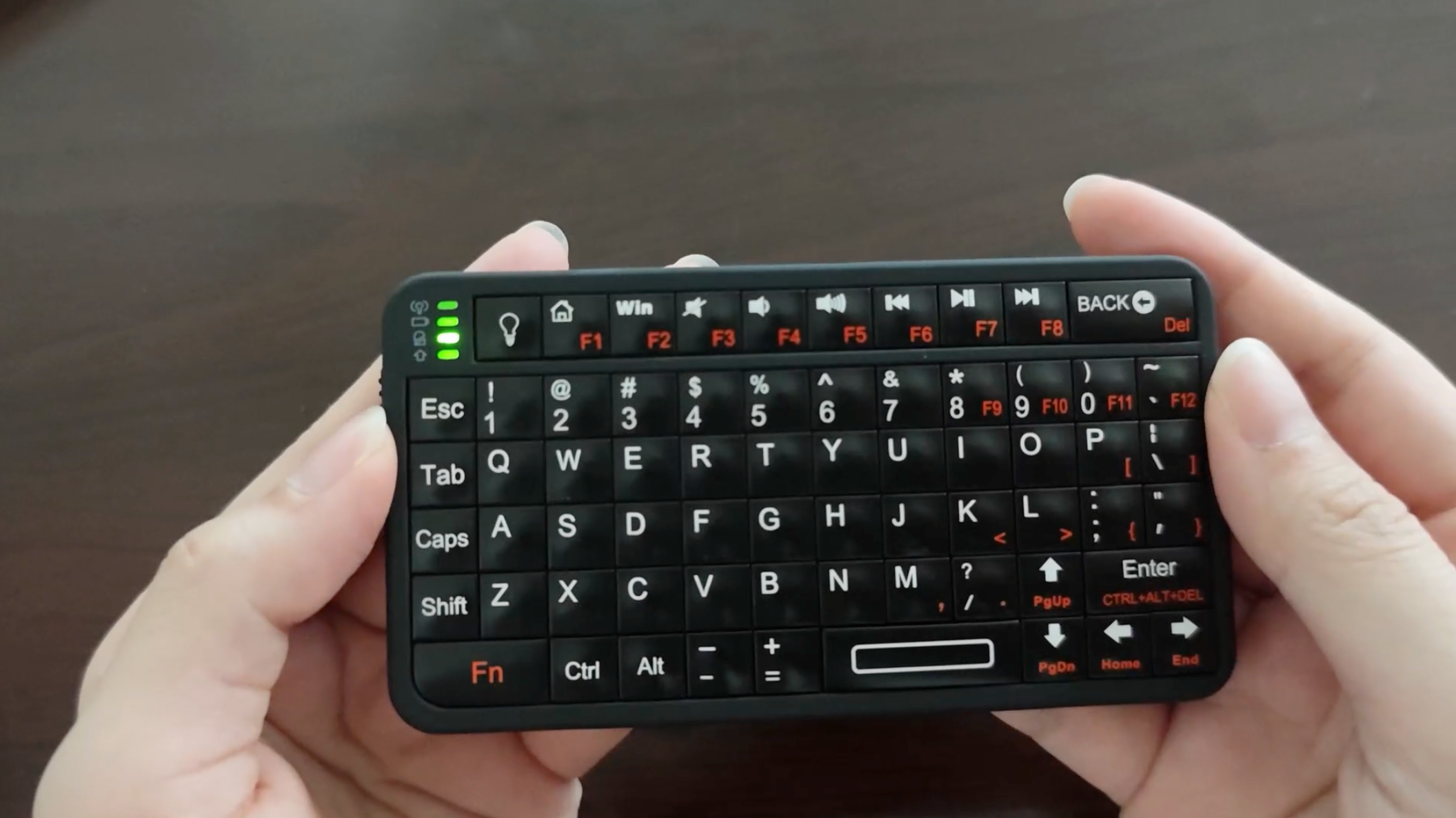 Um mini teclado bluetooth nas mãos em frente a uma mesa de madeira