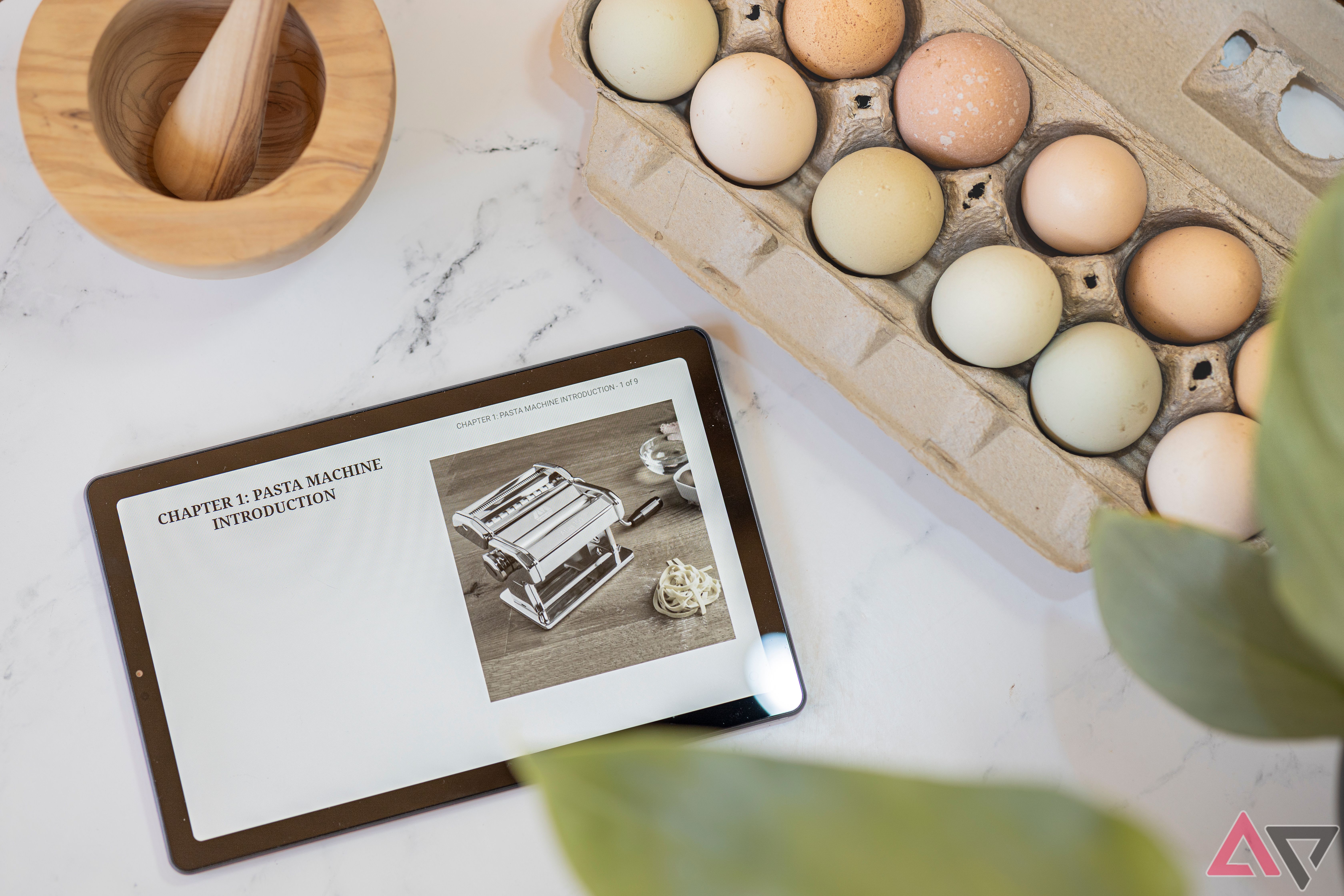 Recanto 9" Lenovo Tablet aberto para livro de receitas de macarrão ao lado de ovos e almofariz e pilão