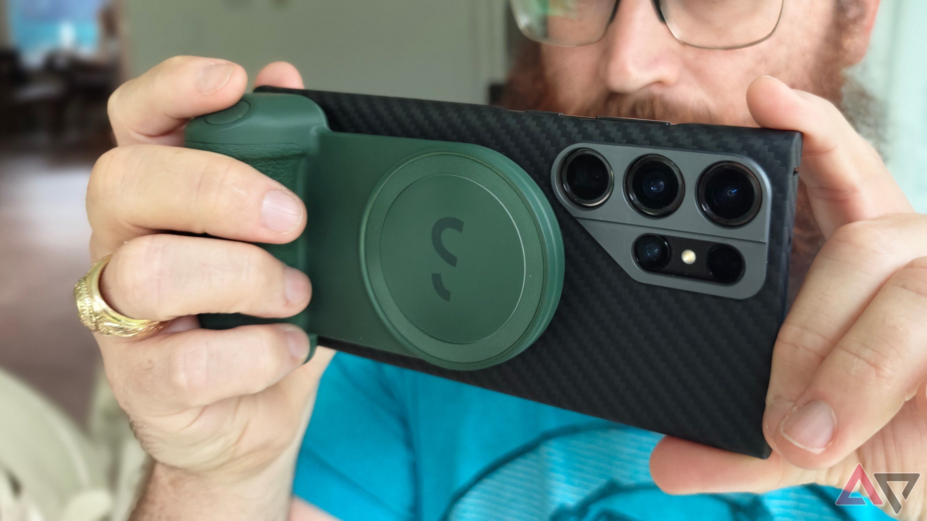ShiftCam SnapGrip sendo usado em um telefone preto por um homem de camisa azul com barba e óculos