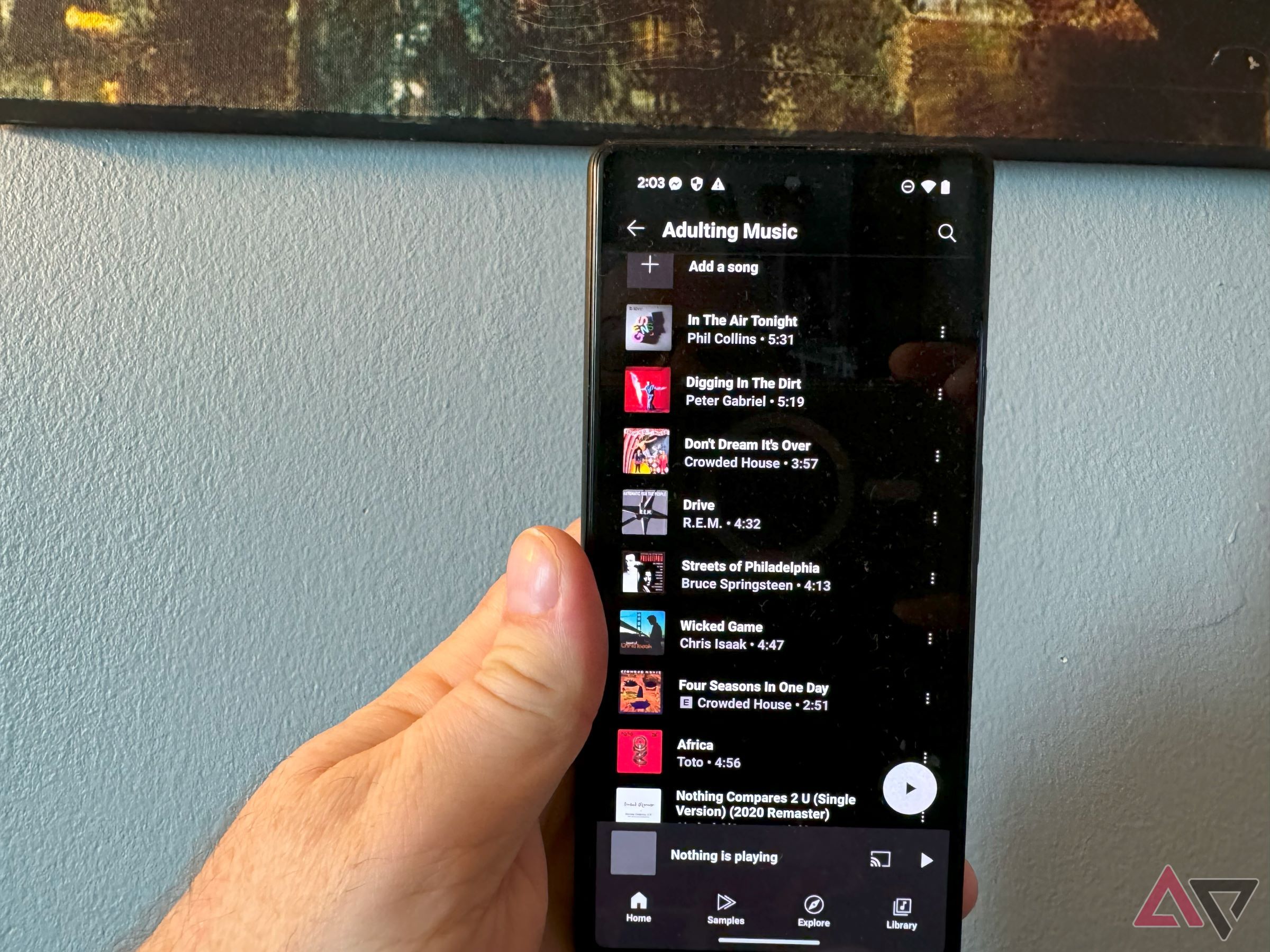 Uma playlist do YouTube Music em um smartphone Pixel na mão de um homem.