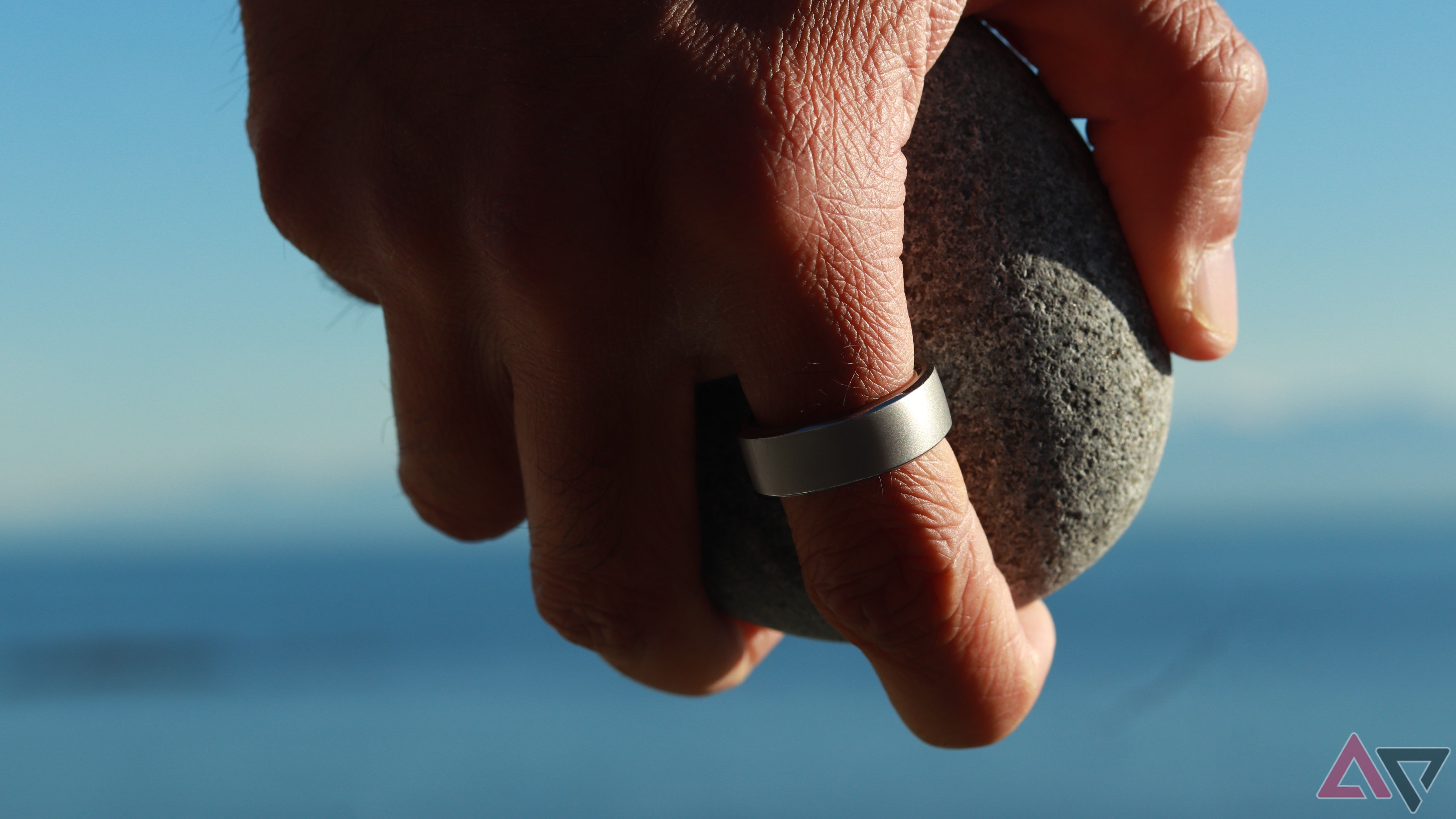 Uma mão usando um anel inteligente segurando uma pedra