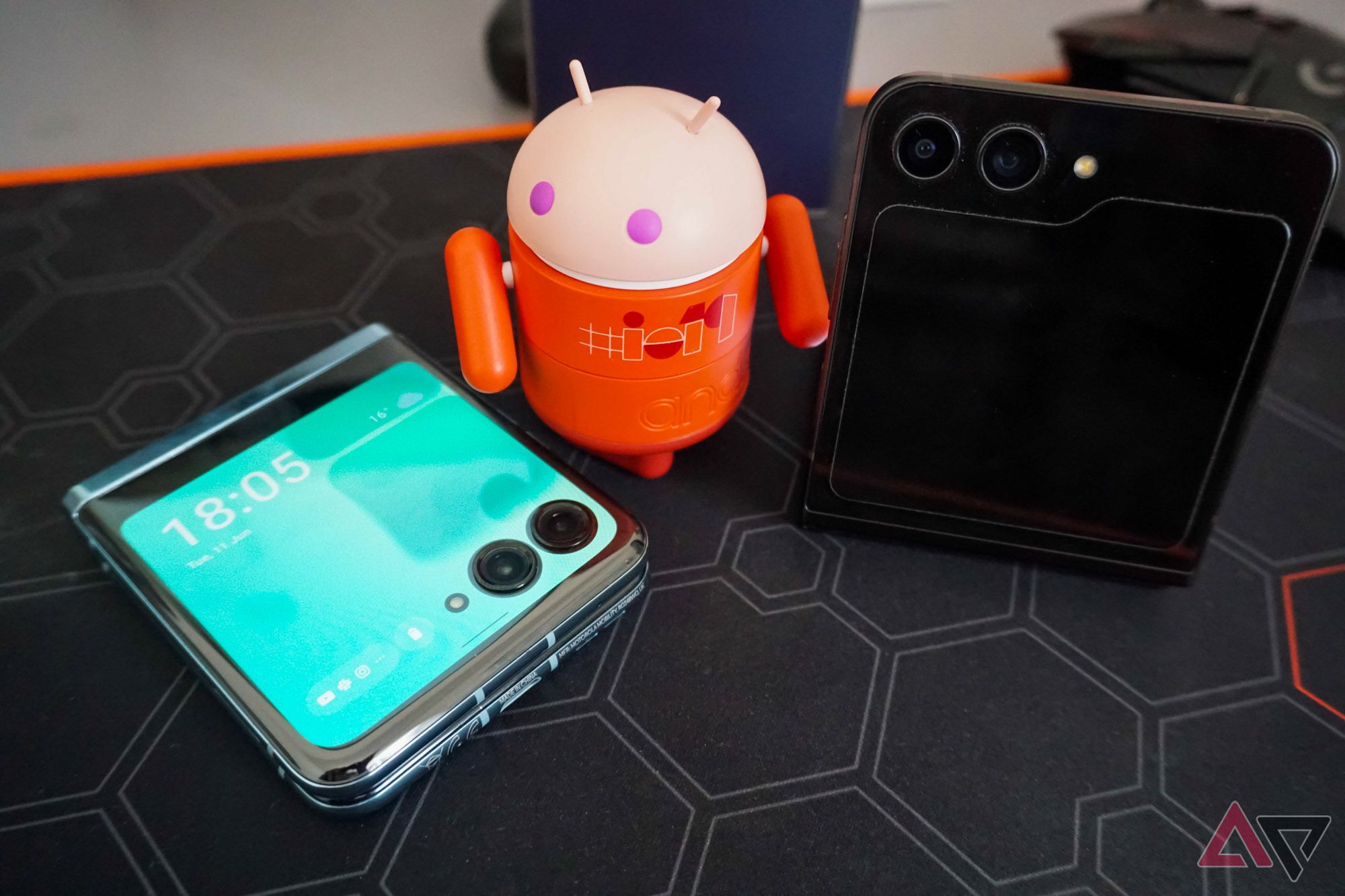 Uma foto de um pequeno Android olhando para um Moto Razr+