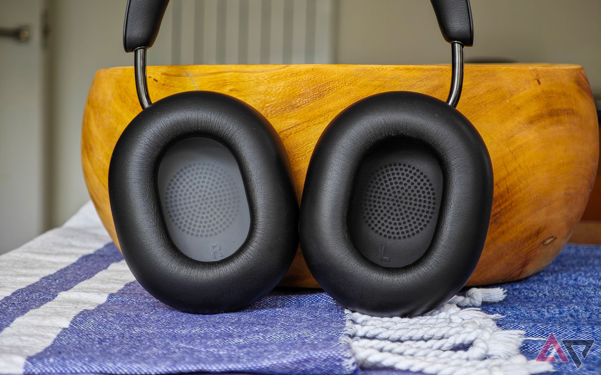 Fones de ouvido Sonos Ace em pé sobre uma mesa, encostados em uma tigela de madeira, com os protetores auriculares internos voltados para a câmera