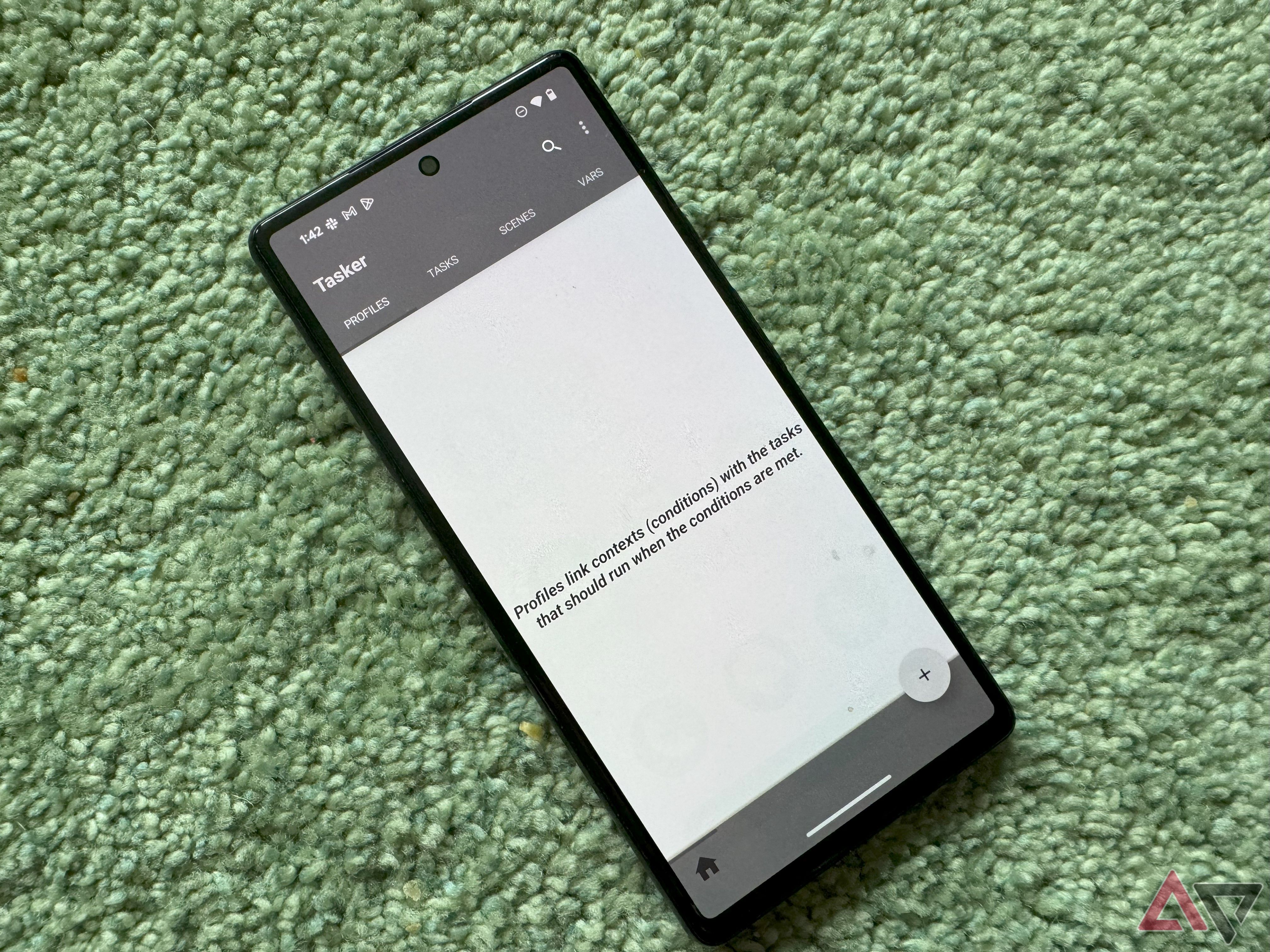 Um smartphone Pixel em um tapete verde com o app Tasker aberto.