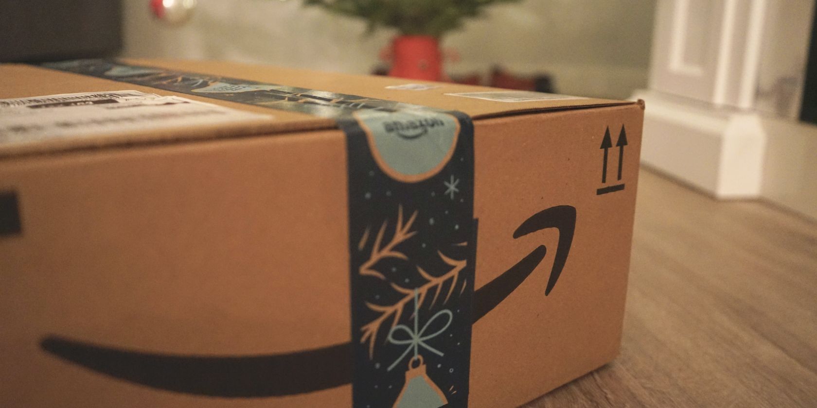 Um pacote Amazon está em primeiro plano com decorações festivas ao fundo.