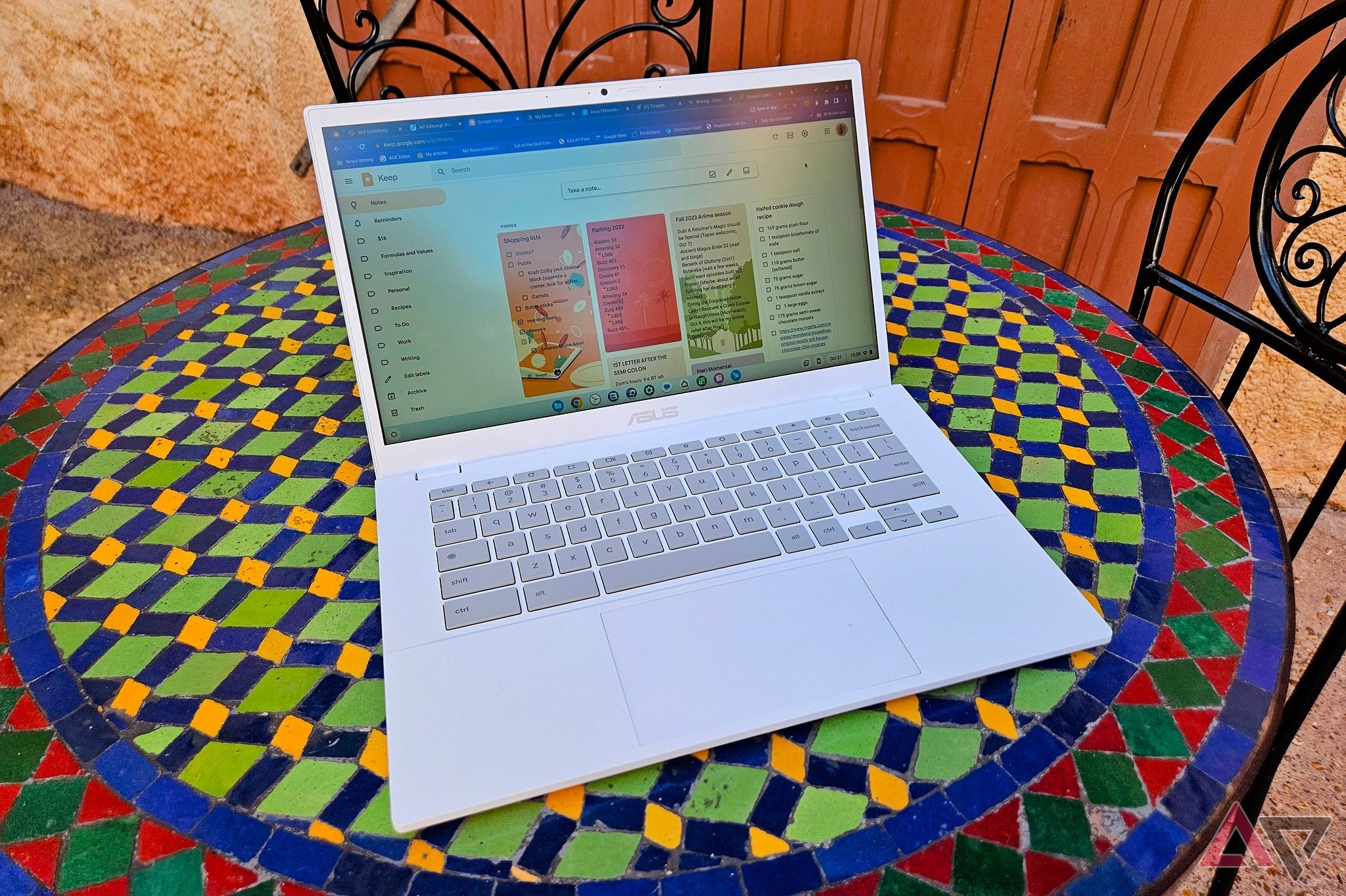 Um Asus Chromebook Plus CX34 em uma mesa de mosaico colorido ao ar livre.