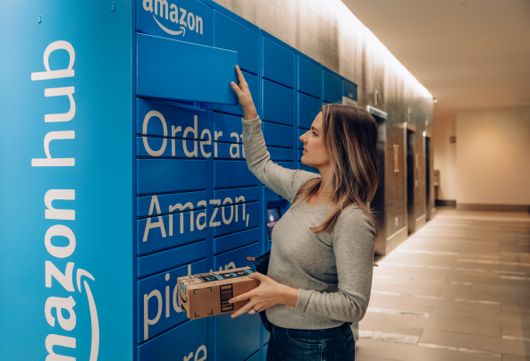 Uma mulher tira um pacote da Amazon de um armário da Amazon. 