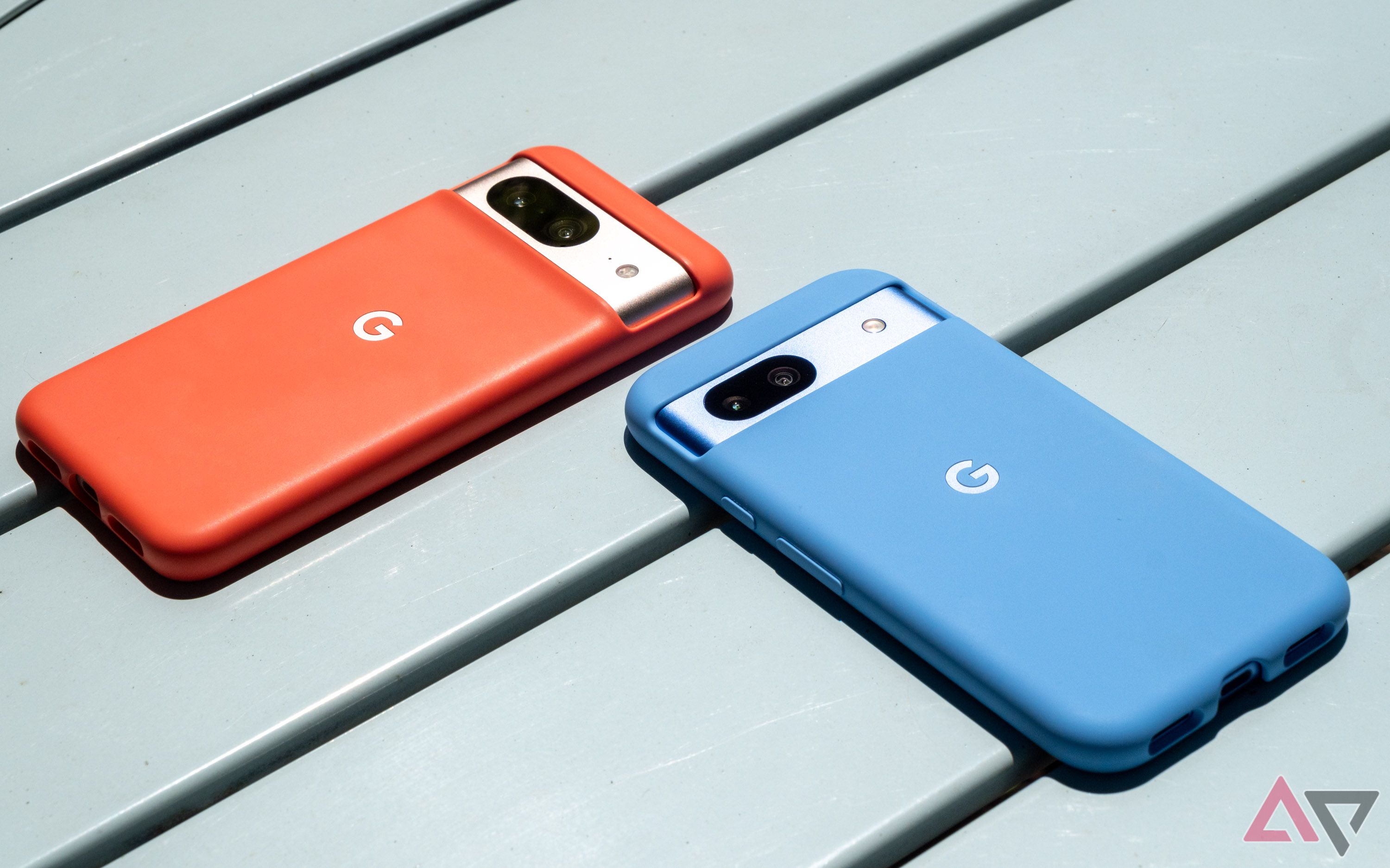 Um smartphone azul e um smartphone laranja em uma mesa de metal
