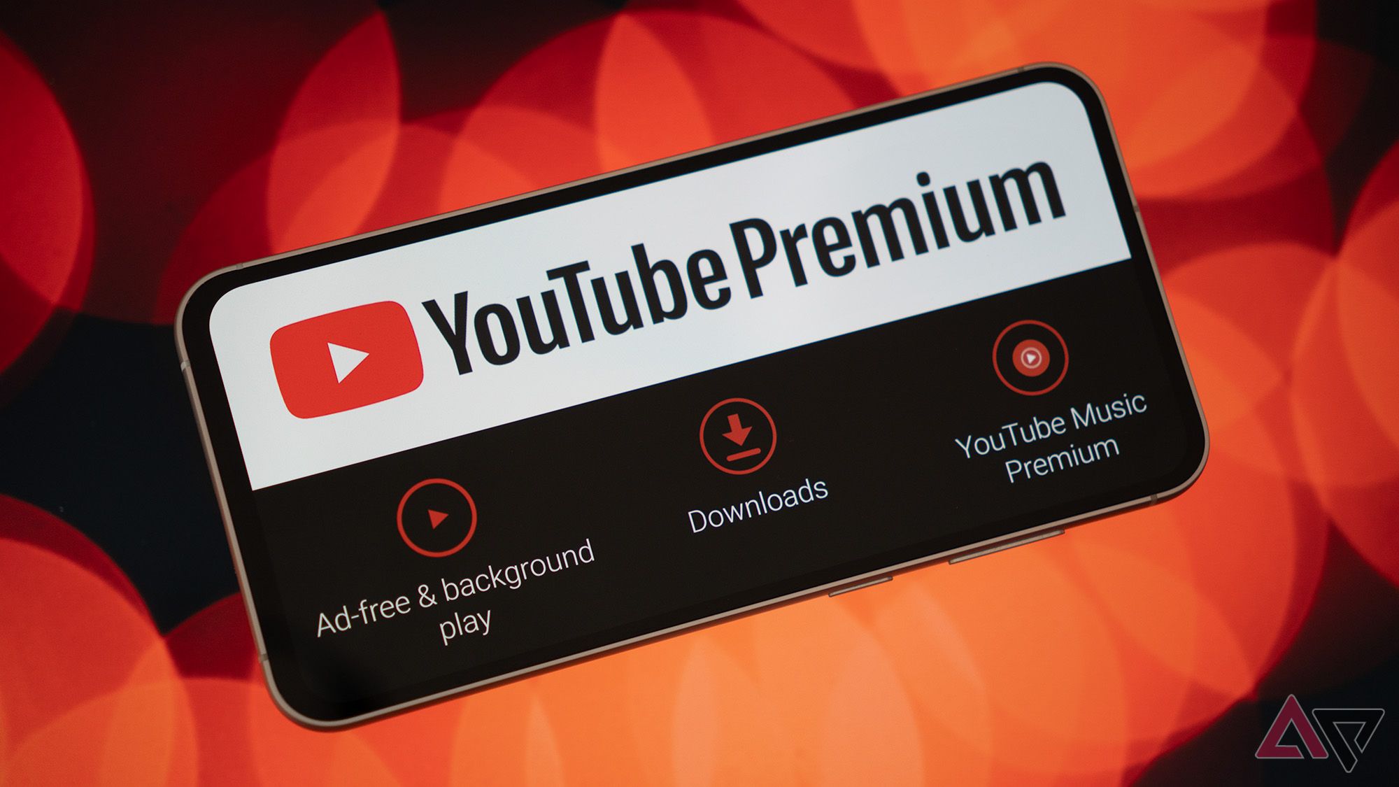 Um telefone exibindo o logotipo e os recursos do YouTube Premium em um fundo bokeh vermelho.