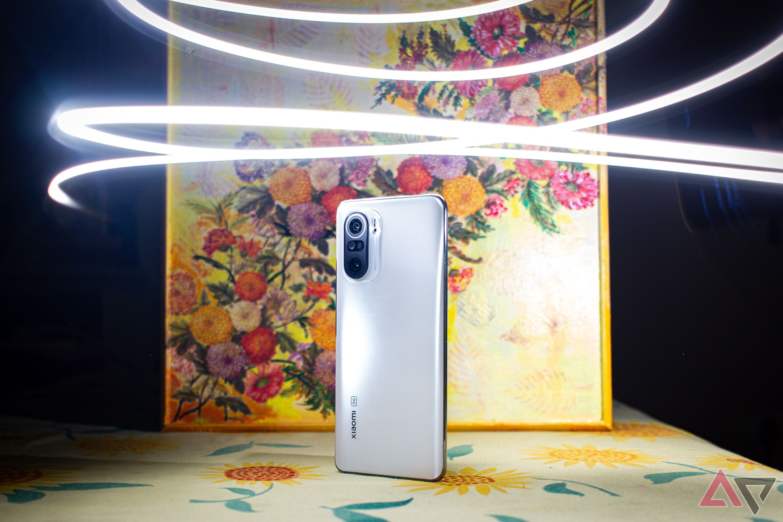 Um telefone contra um fundo floral amarelo iluminado por rastros de luz branca 