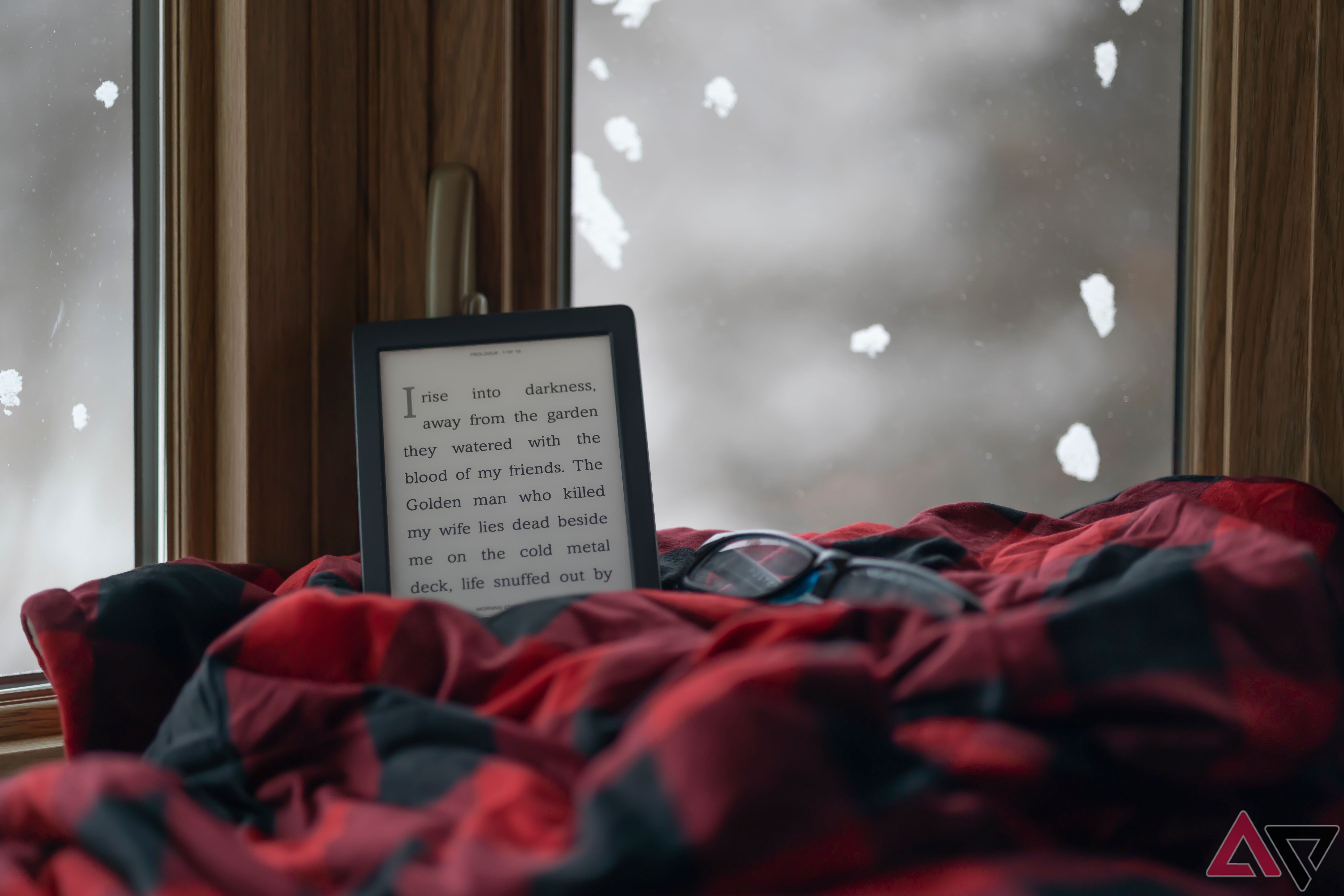 Tablet de leitura Kobo Nia e óculos de leitura em cobertor xadrez vermelho e preto