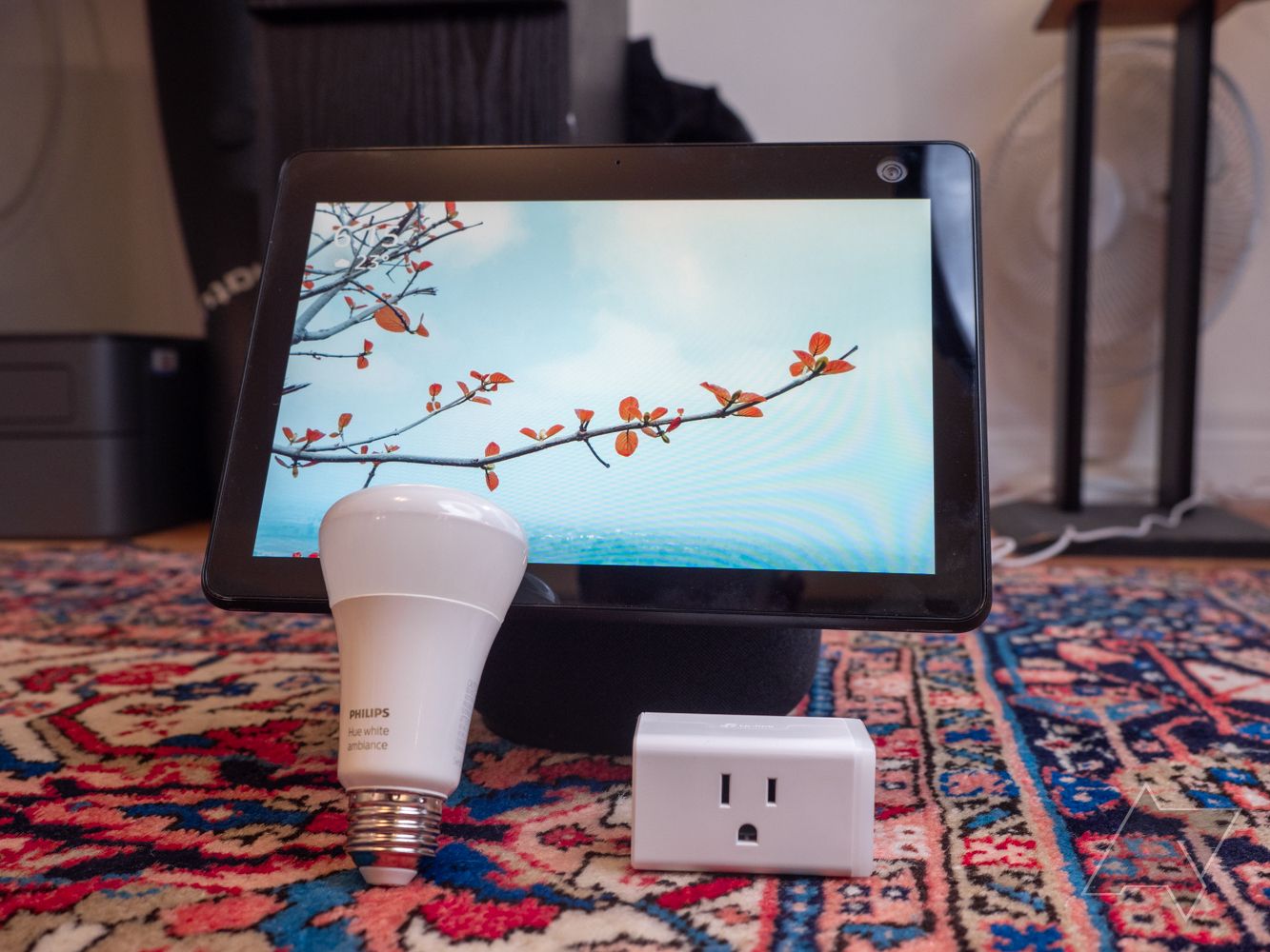 Um display inteligente, uma lâmpada inteligente e um plugue de energia inteligente em um tapete multicolorido