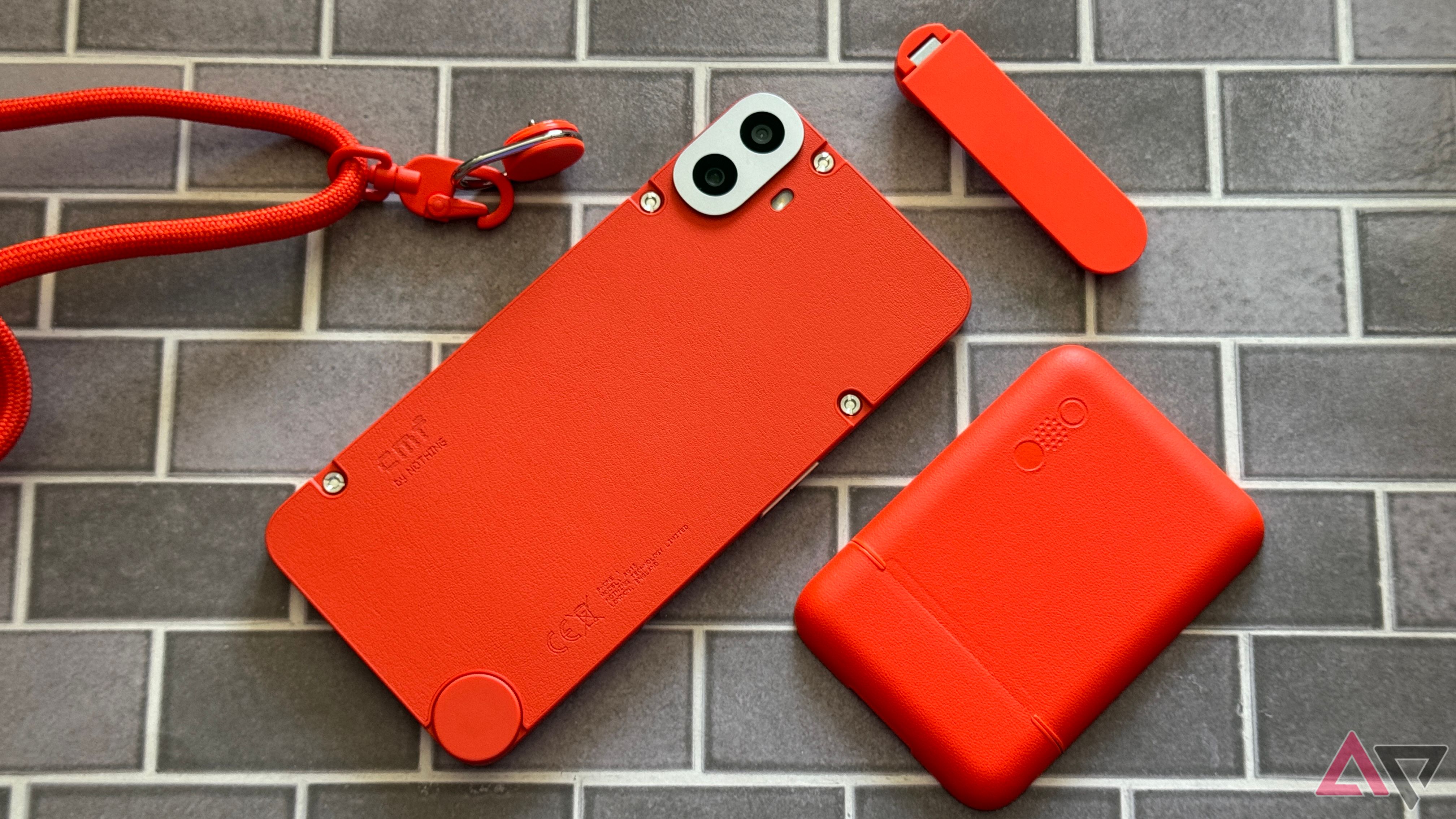 CMF Phone 1 em laranja cercado por capa carteira, suporte e acessórios de cordão
