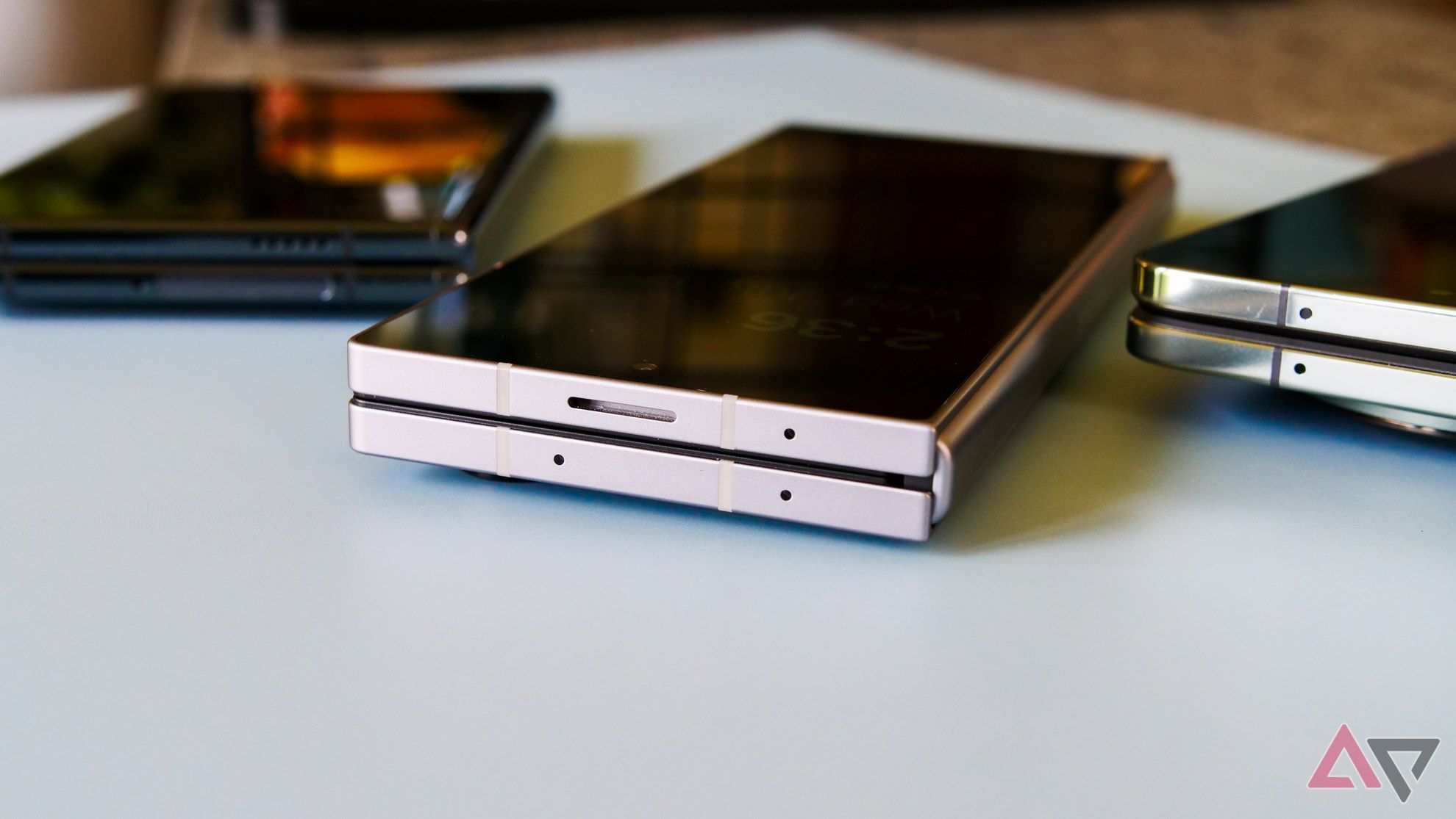 O Galaxy Z Fold 6, o OnePlus Open e o Pixel Fold sobre uma mesa com as saliências das câmeras voltadas para baixo.