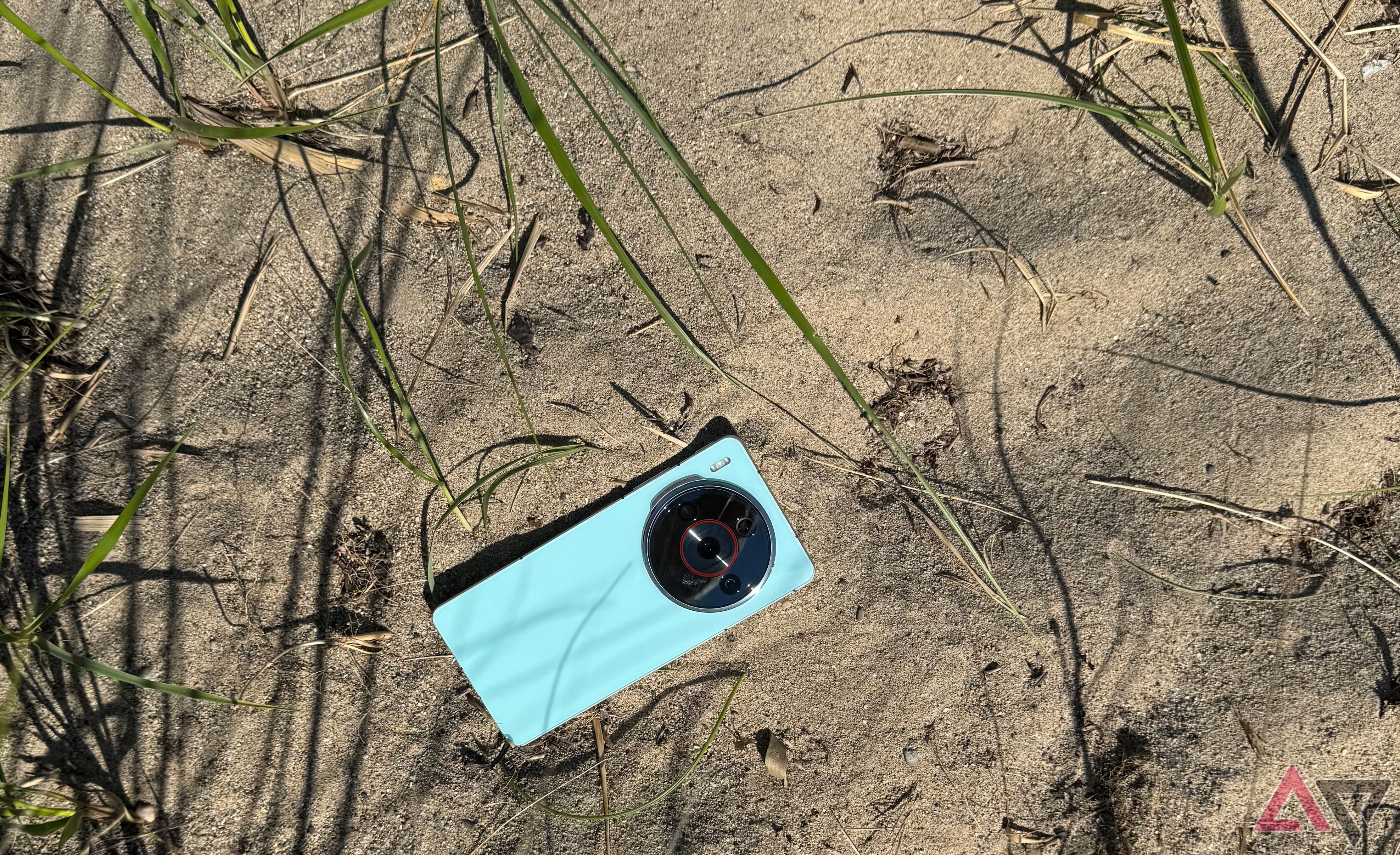 Uma Nubia Z60S Pro na cor água na areia cercada por grama de praia.