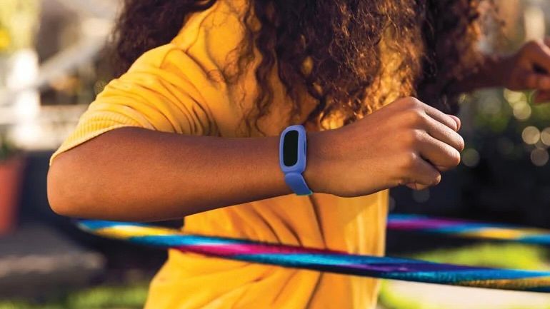 Criança usando Fitbit Ace 3 com bambolê e vestindo uma camisa amarela