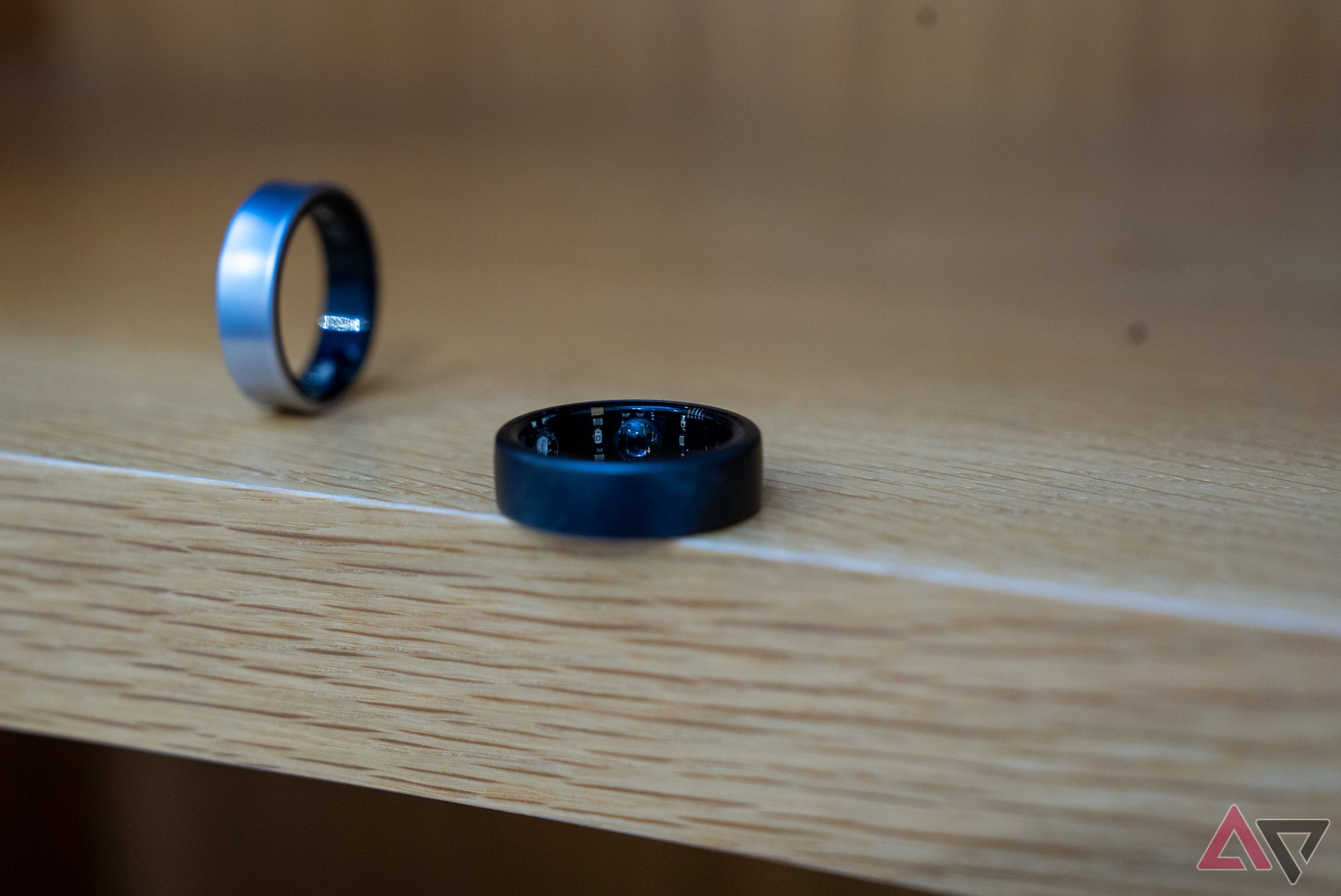 Oura Ring plano em uma prateleira ao lado de um Galaxy Ring vertical