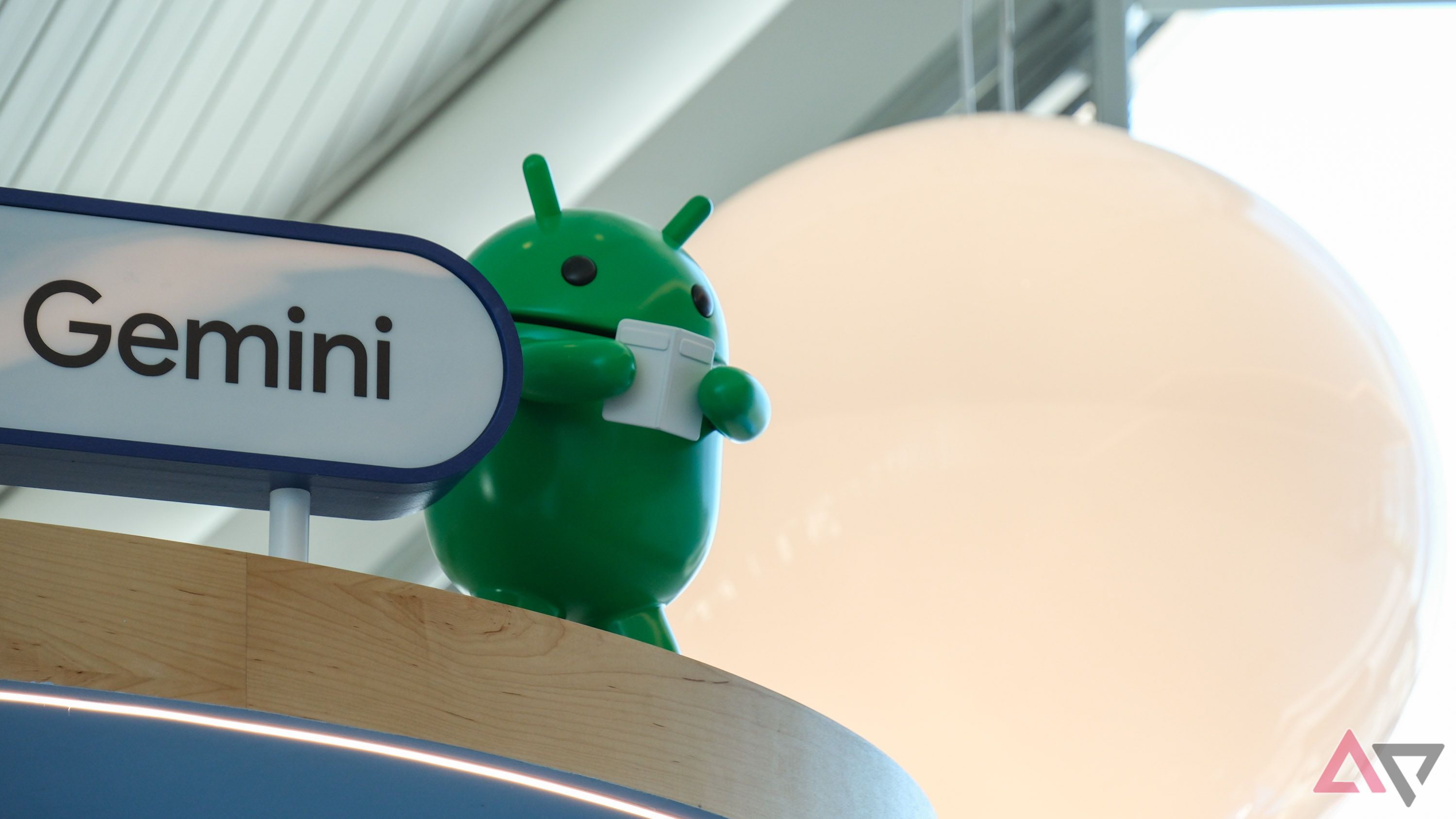 Um mascote robô Android ao lado de uma placa que diz 