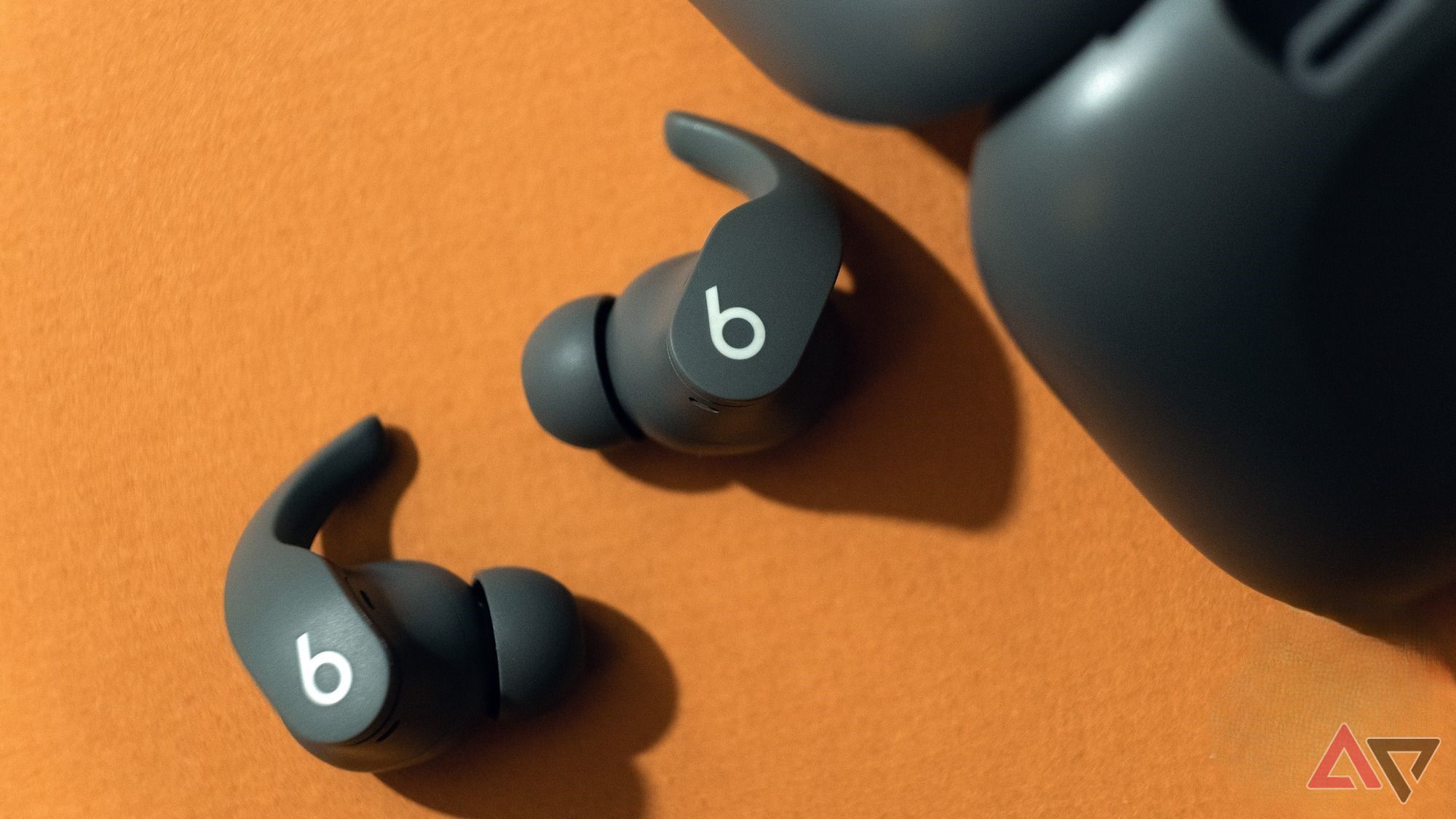 beats fit pro deitado na frente da caixa em fundo laranja