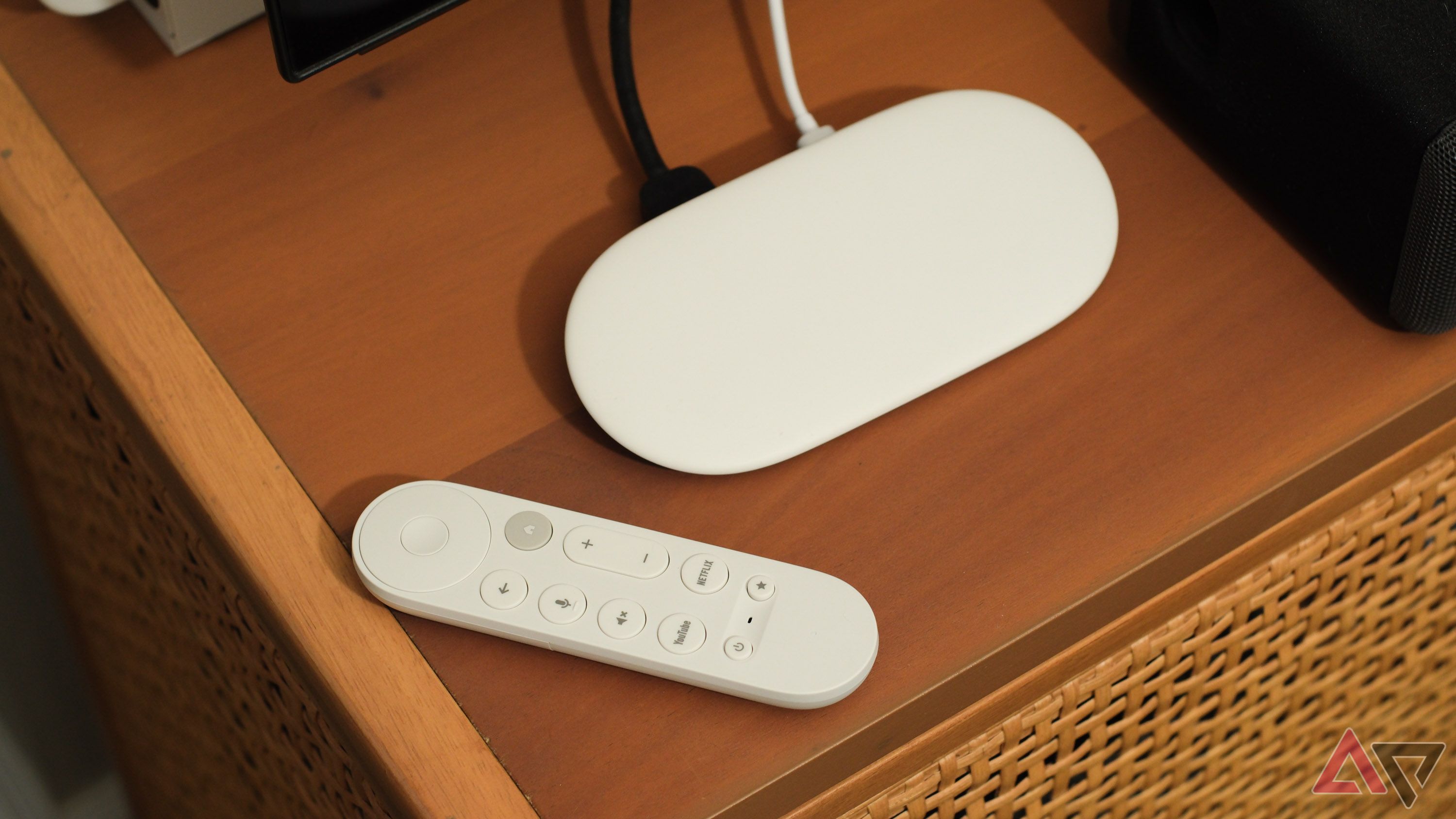 O Google TV Streamer com controle remoto em um suporte de TV.