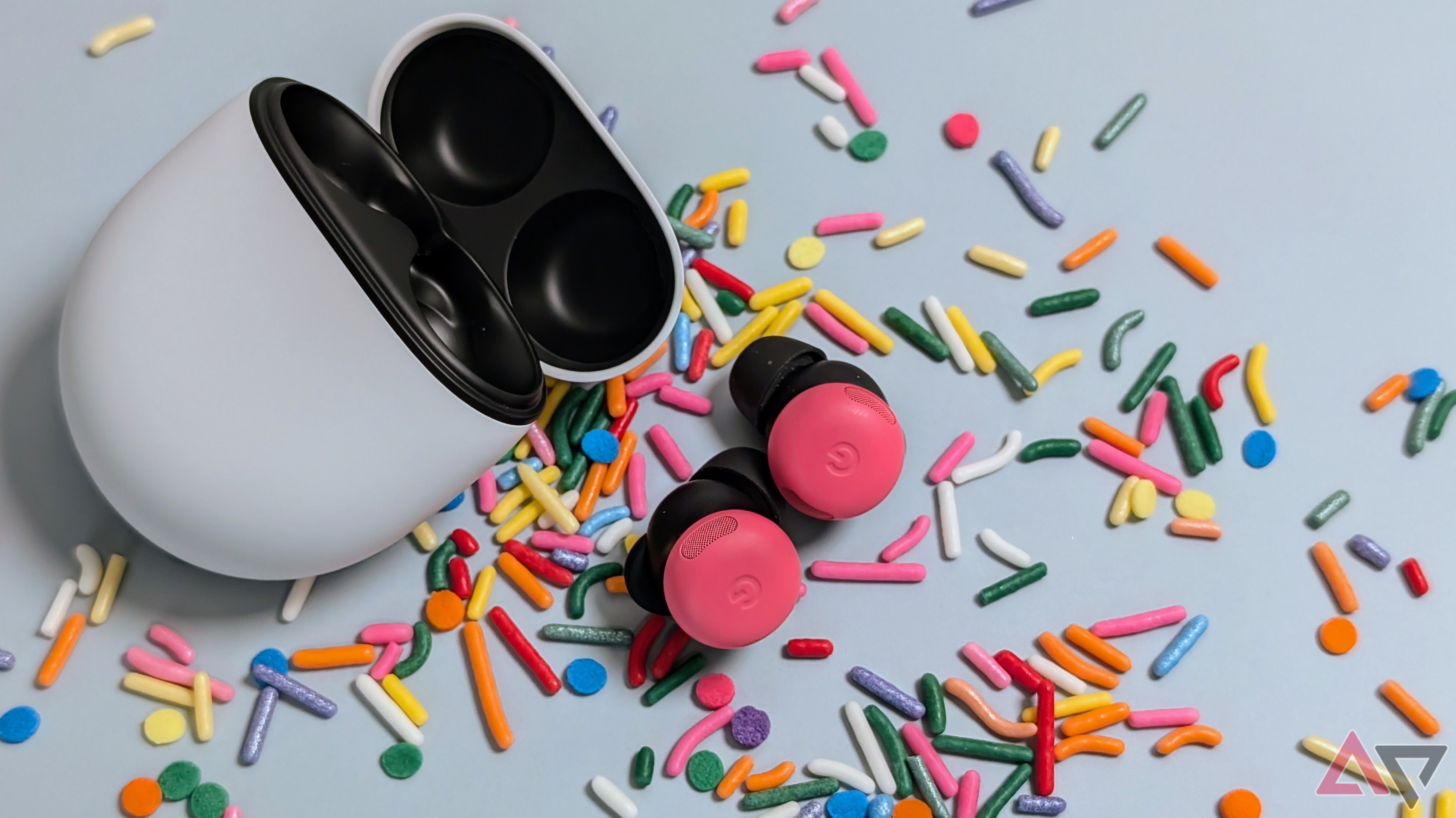 Caixa aberta do Google Pixel Buds Pro 2 com botões de peônia na mesa cercada por granulados