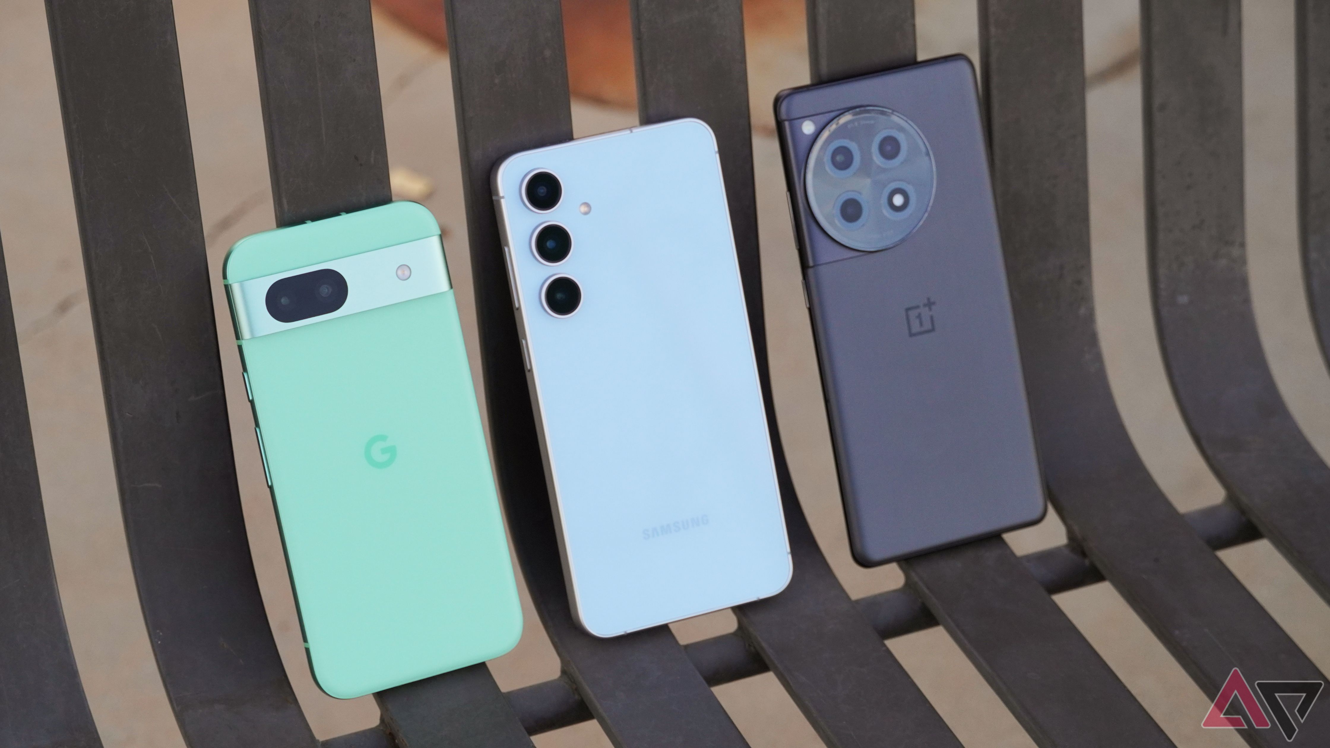 O Google Pixel 8a, Galaxy S24 FE e OnePlus 12R em uma bancada.