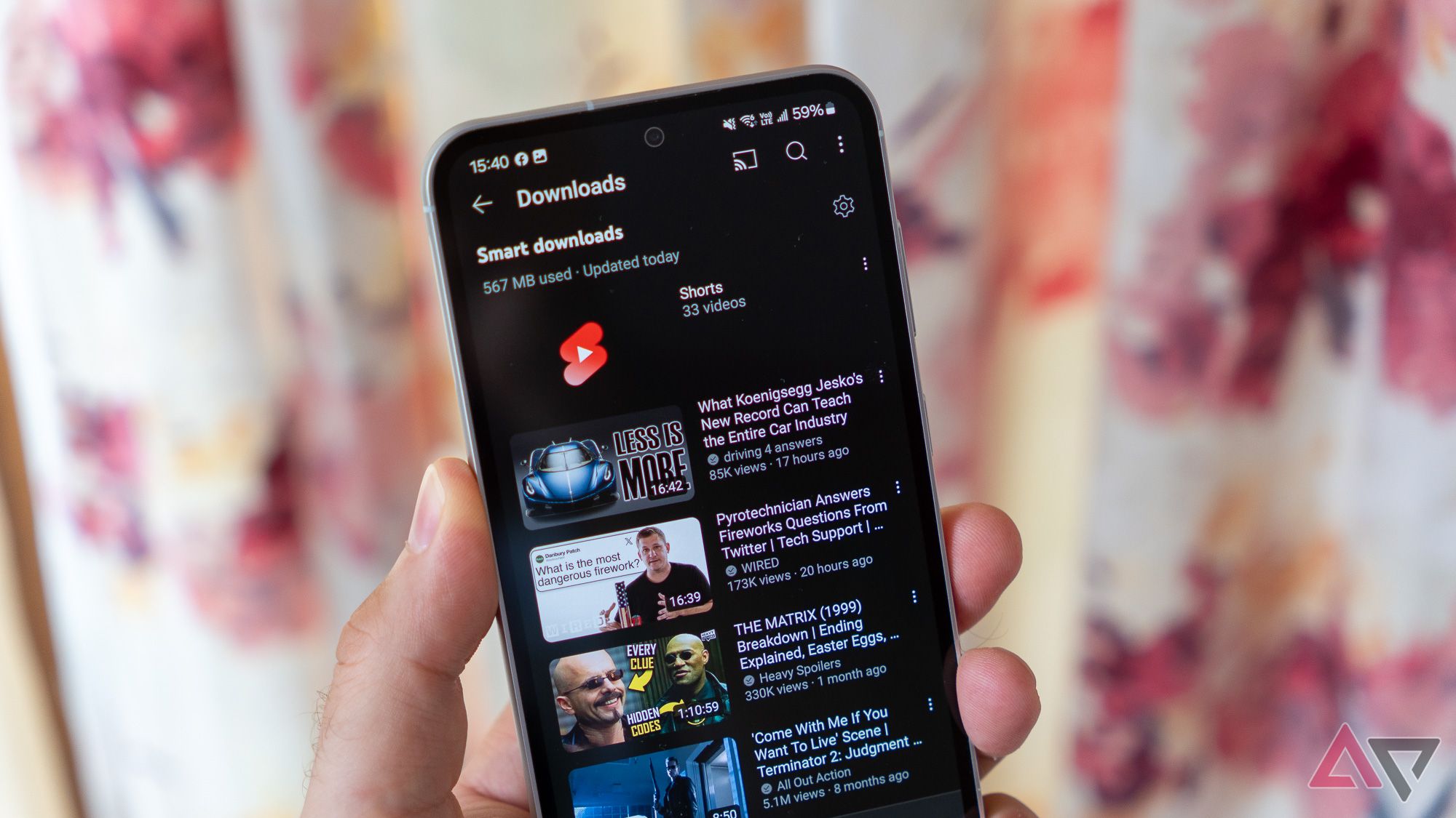 Downloads do YouTube Premium exibidos em um telefone Samsung na mão.