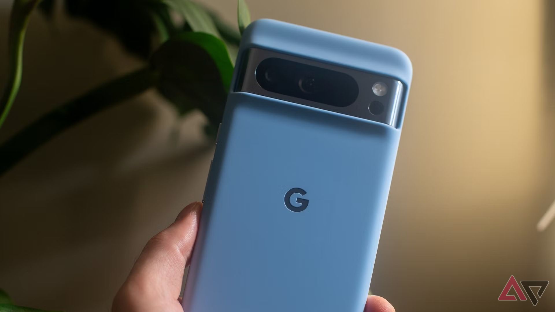 O Pixel 8 Pro em sua capa azul do Google, segurado na mão