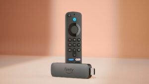 The Amazon Fire TV Stick 4K and remote control against a pinkish-brown background.